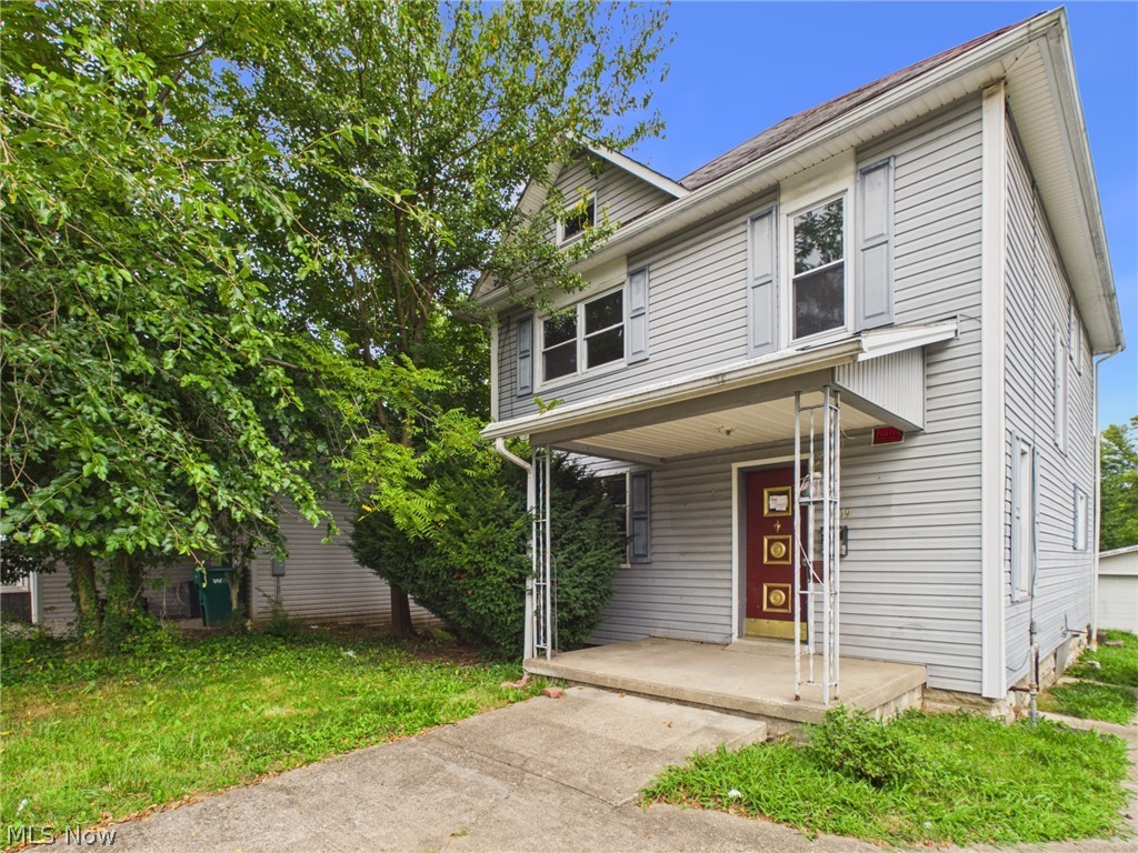 Two-story gray-sided office with a red front door, covered porch, and tree-lined lawn.