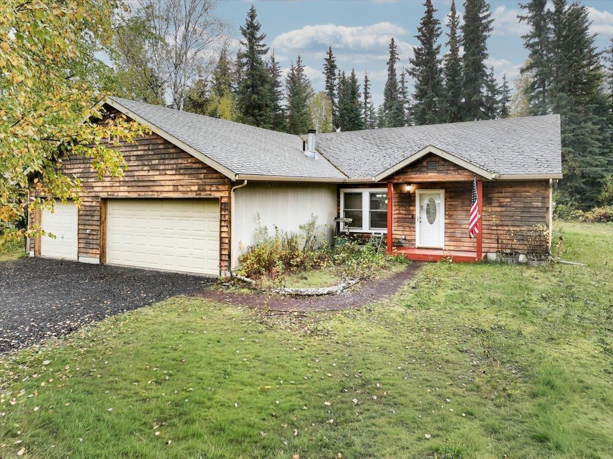 Single-story wood-sided home with two garage doors, a covered entry, and a broad lawn.
