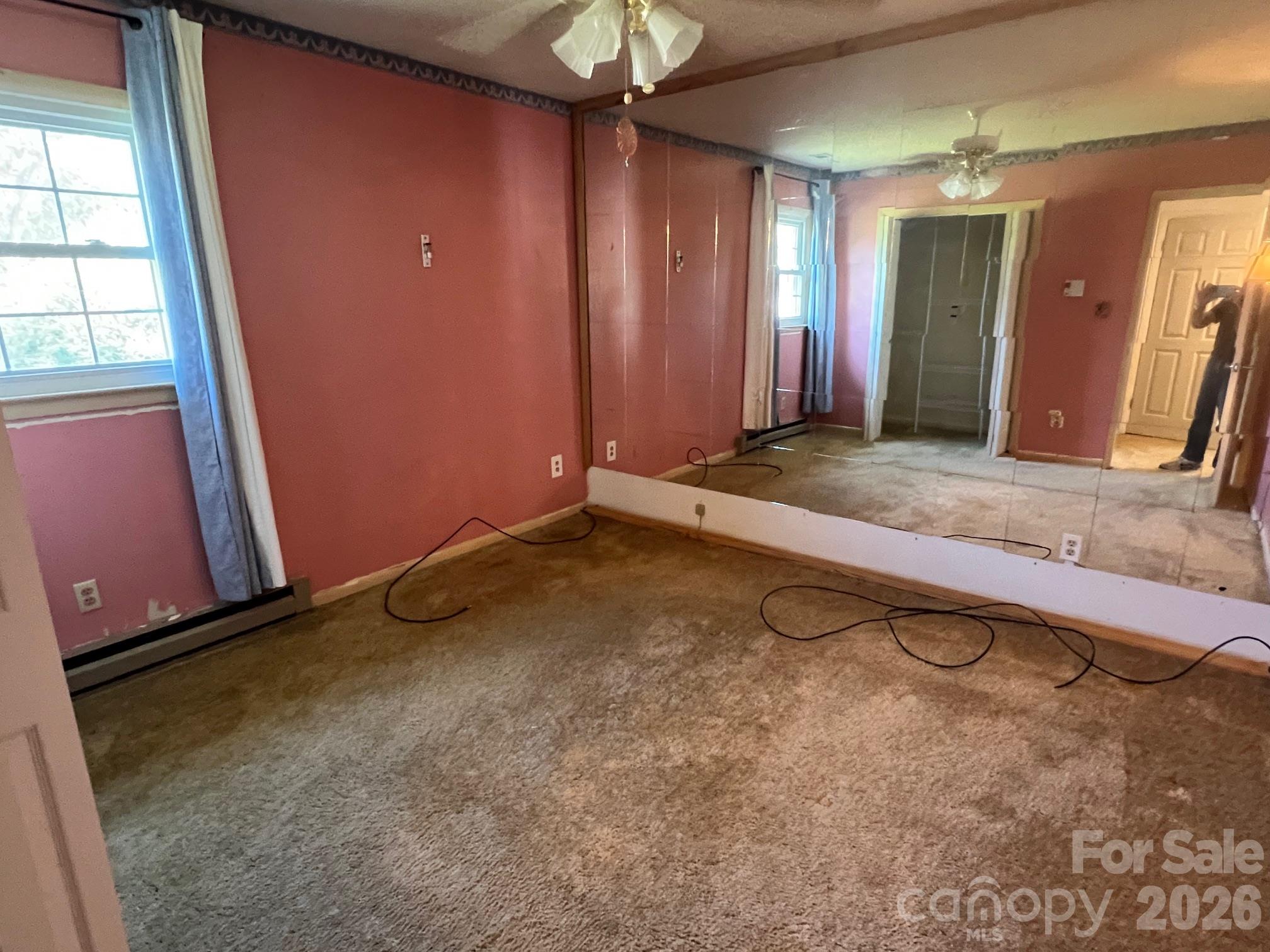 Empty carpeted bedroom with rose walls and a mirrored closet wall.