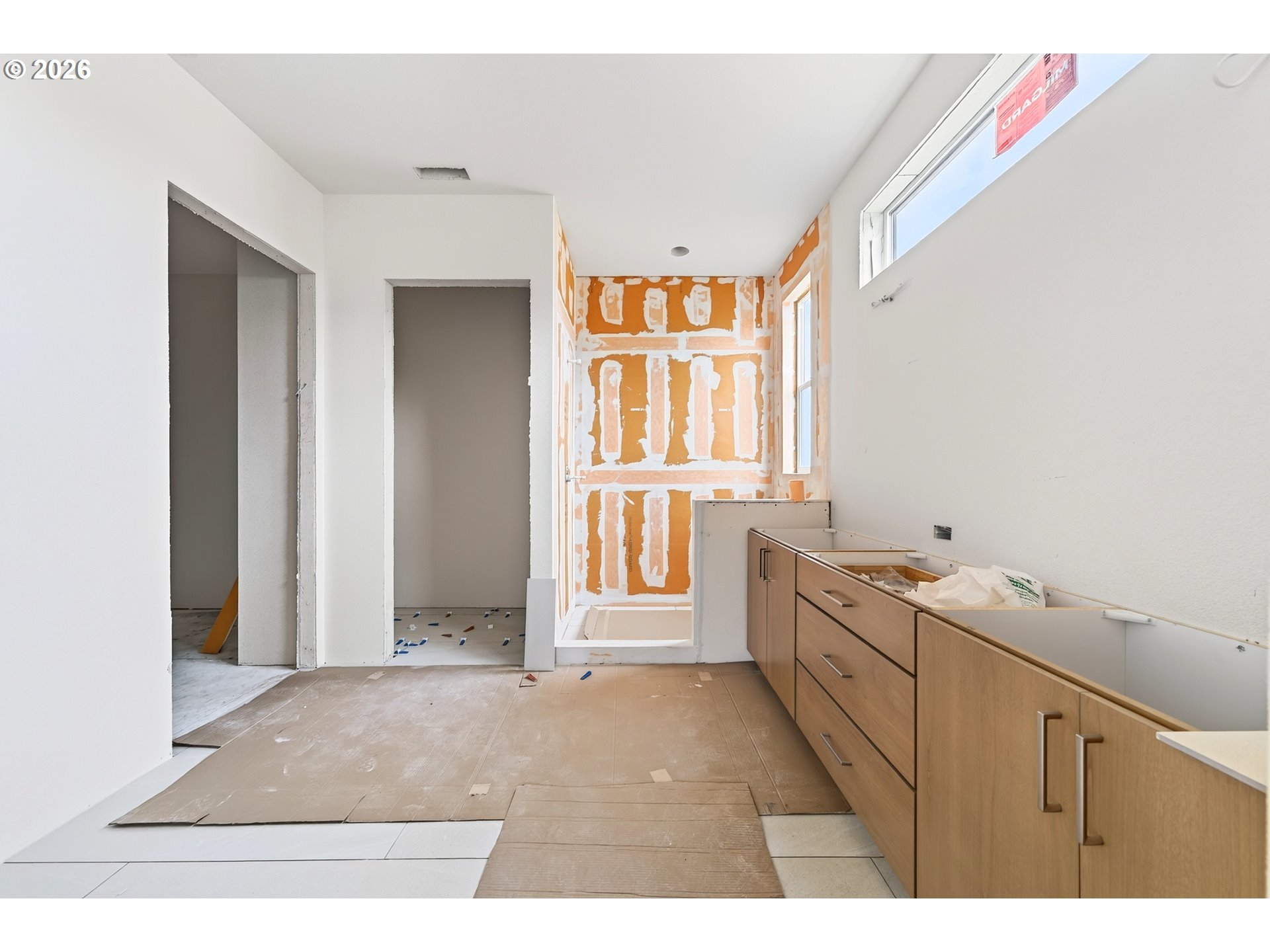 Unfinished kitchen with wood cabinets, exposed drywall seams, and floor protection.