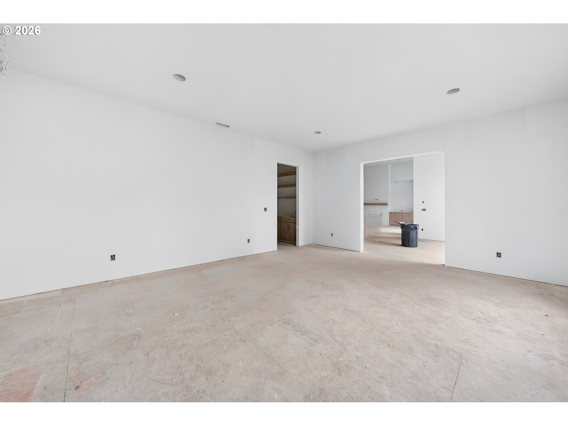 Unfinished empty room with concrete floor and open doorways to adjoining rooms.