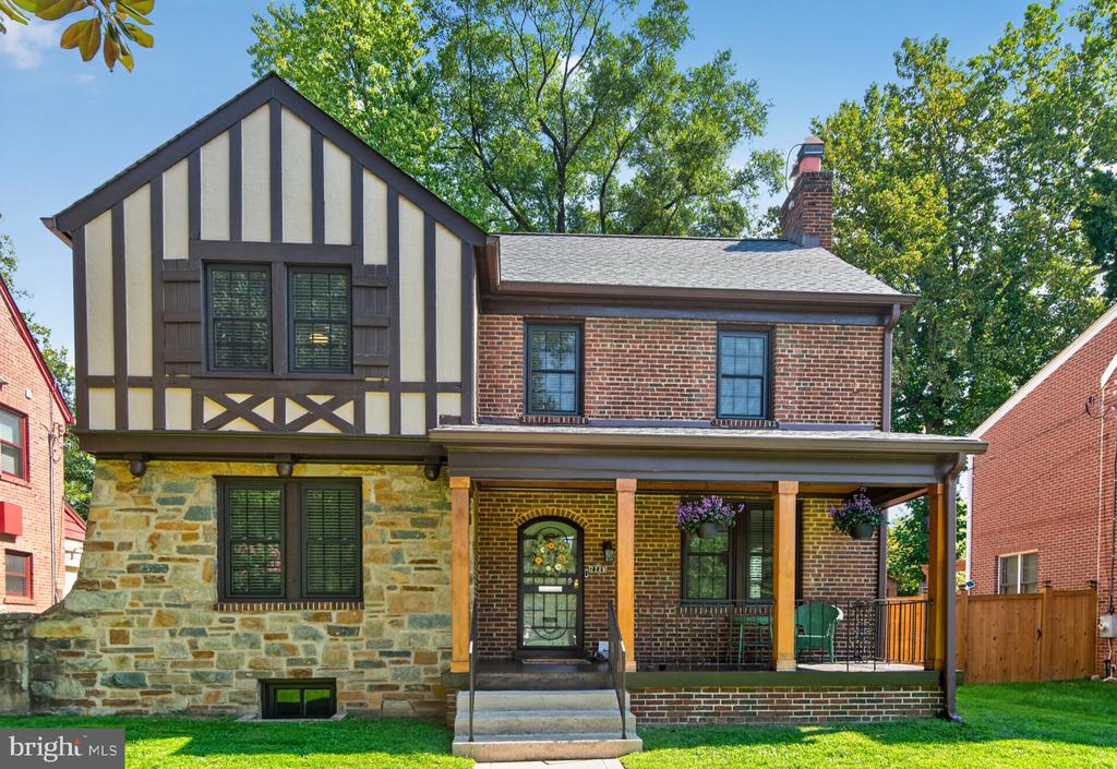 Two-story brick and stone home with Tudor-style upper facade and a covered porch.
