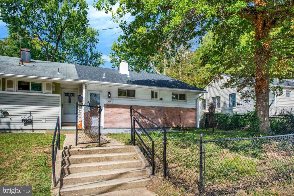Single-story home with a brick facade, fenced yard, and concrete front steps.