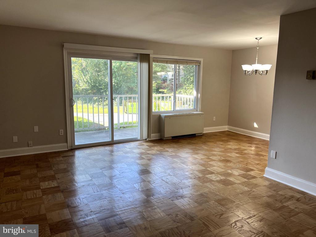 Empty living and dining area with parquet floors and sliding glass doors to a balcony.