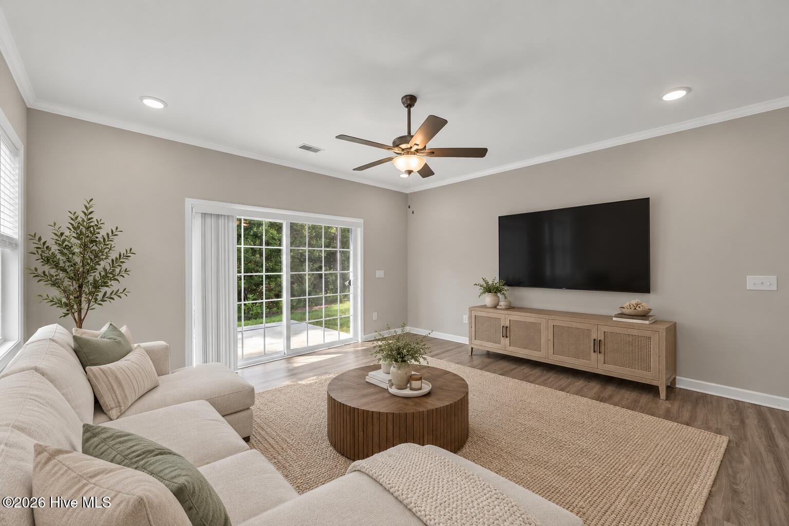 Living room with a cream sectional, round coffee table, and sliding glass doors to a patio.