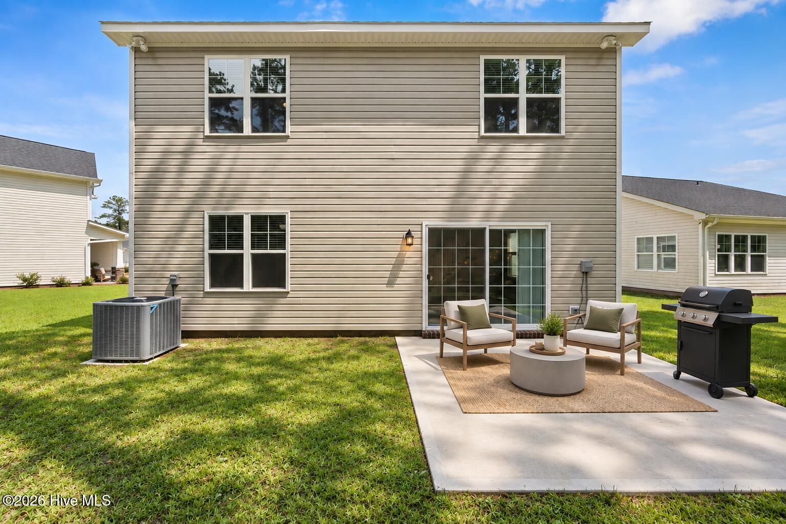 Rear of a two-story home with a furnished patio, outdoor rug, and barbecue grill.