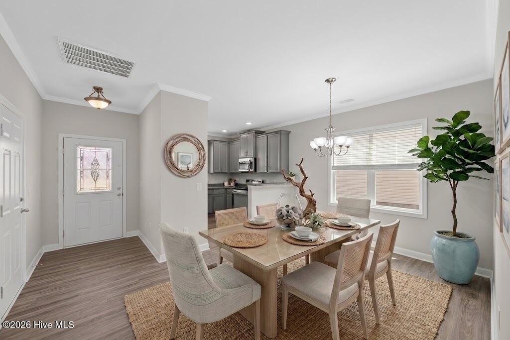 Dining room with a set table, upholstered chairs, woven rug, and a view into the kitchen.
