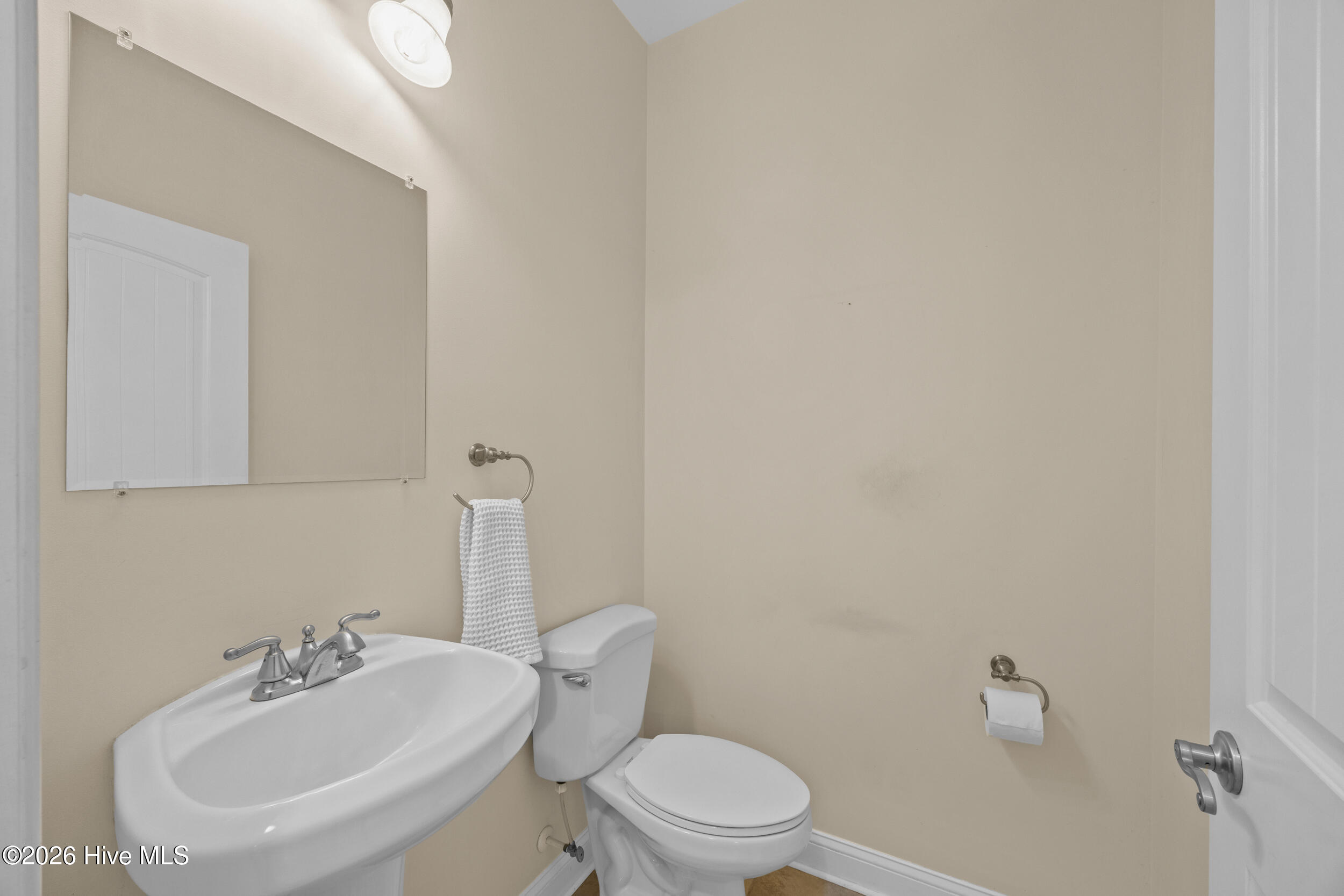 Bathroom with a white pedestal sink, toilet, and large wall mirror.