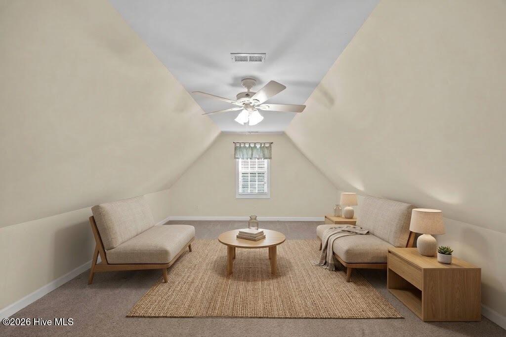 Upstairs sitting area with sloped ceilings, two beige sofas, and a round coffee table.