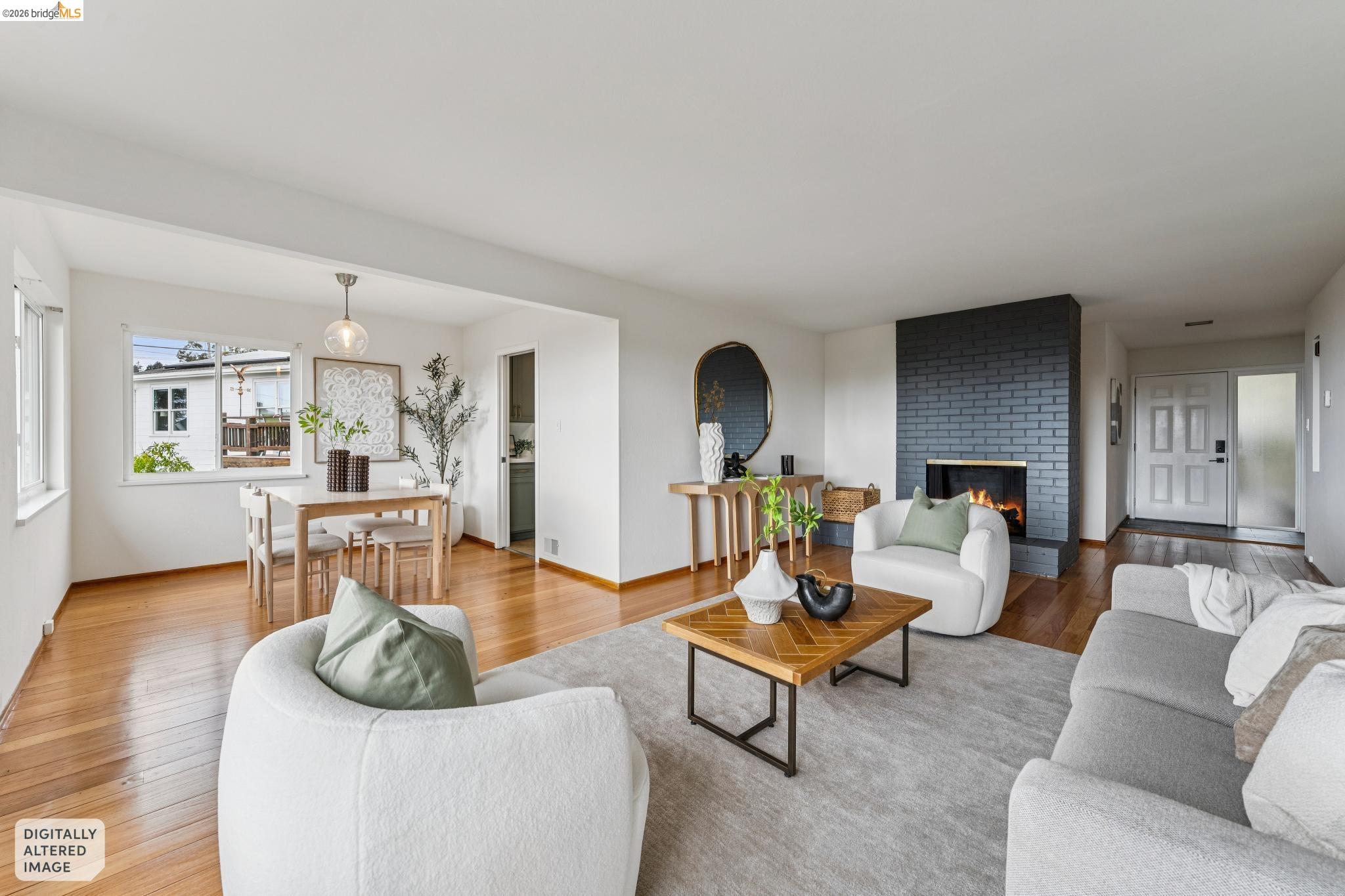 Staged living and dining room with hardwood floors and a dark blue brick fireplace.