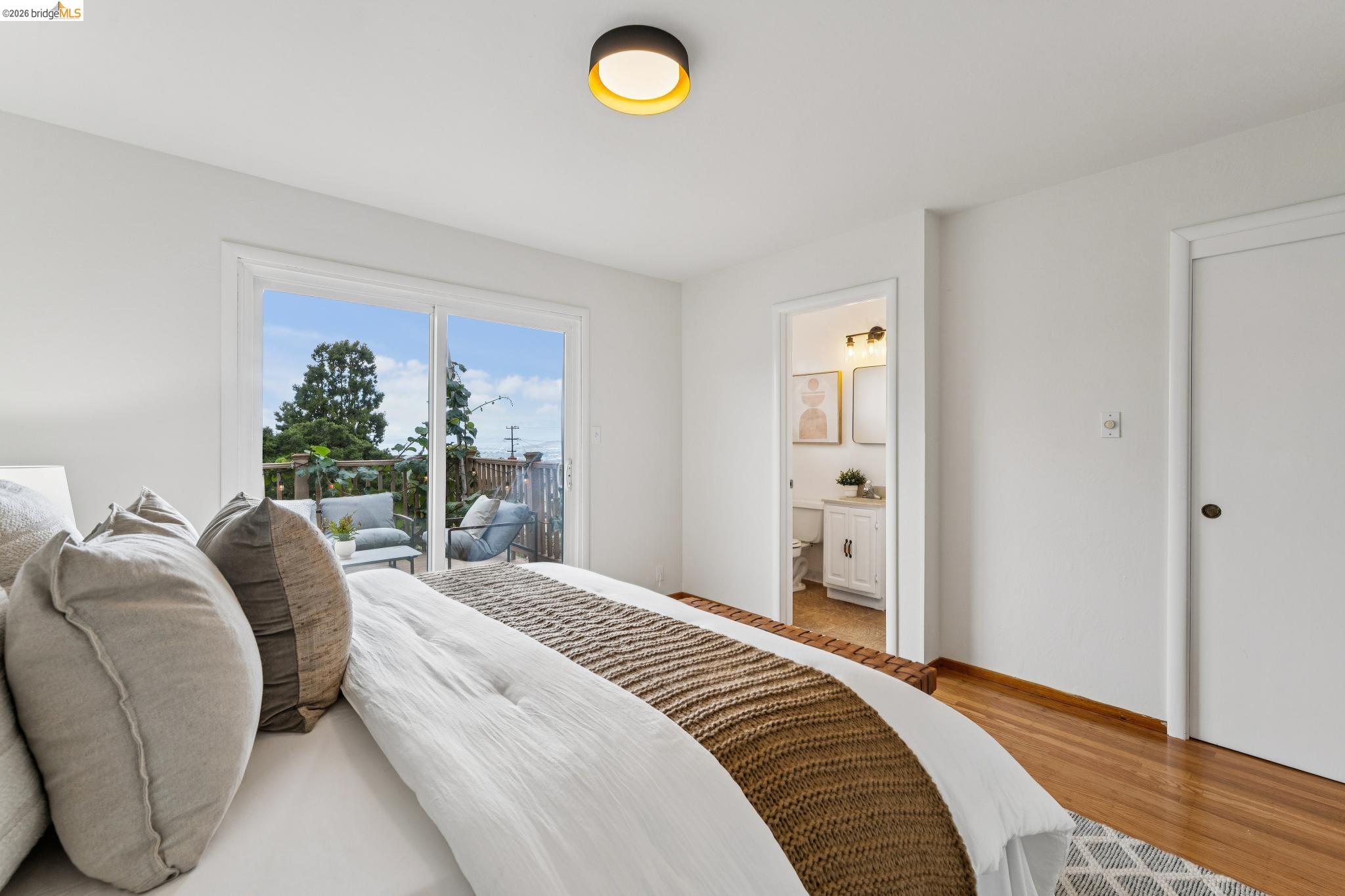 Bedroom with a white bed, sliding doors to a deck, and an ensuite bathroom doorway.