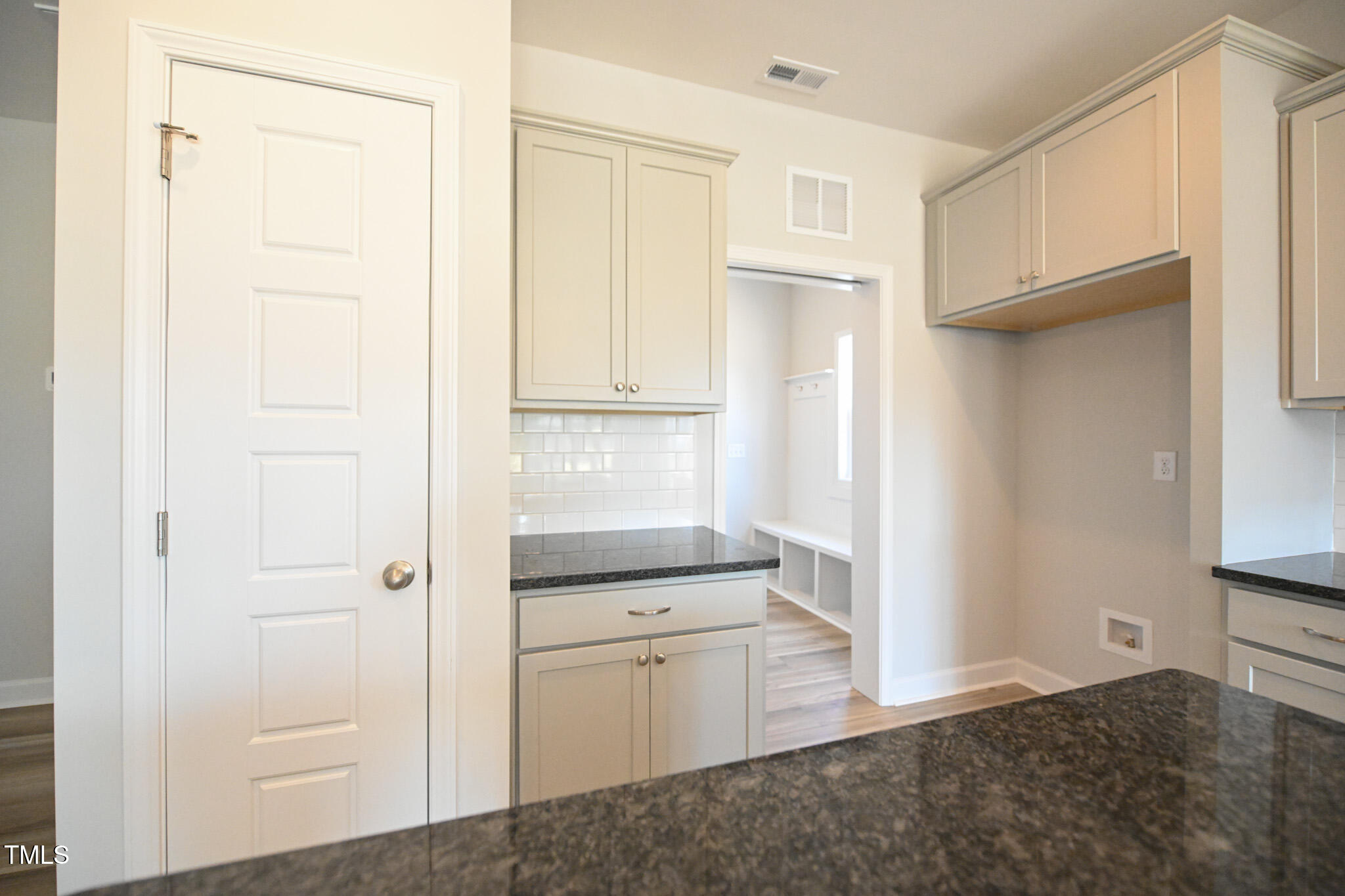 Kitchen with light cabinetry, granite counters, and a white subway-tile backsplash.