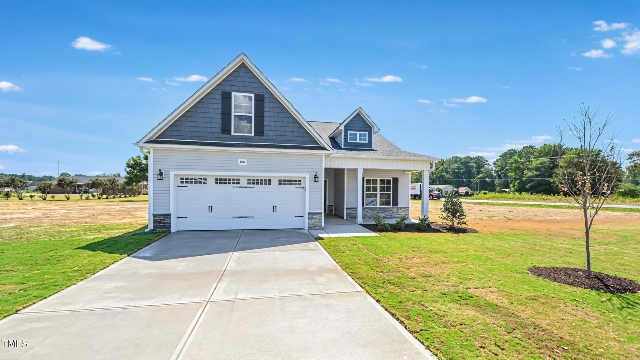 Gray-blue house with a two-car garage, covered porch, and wide concrete driveway.