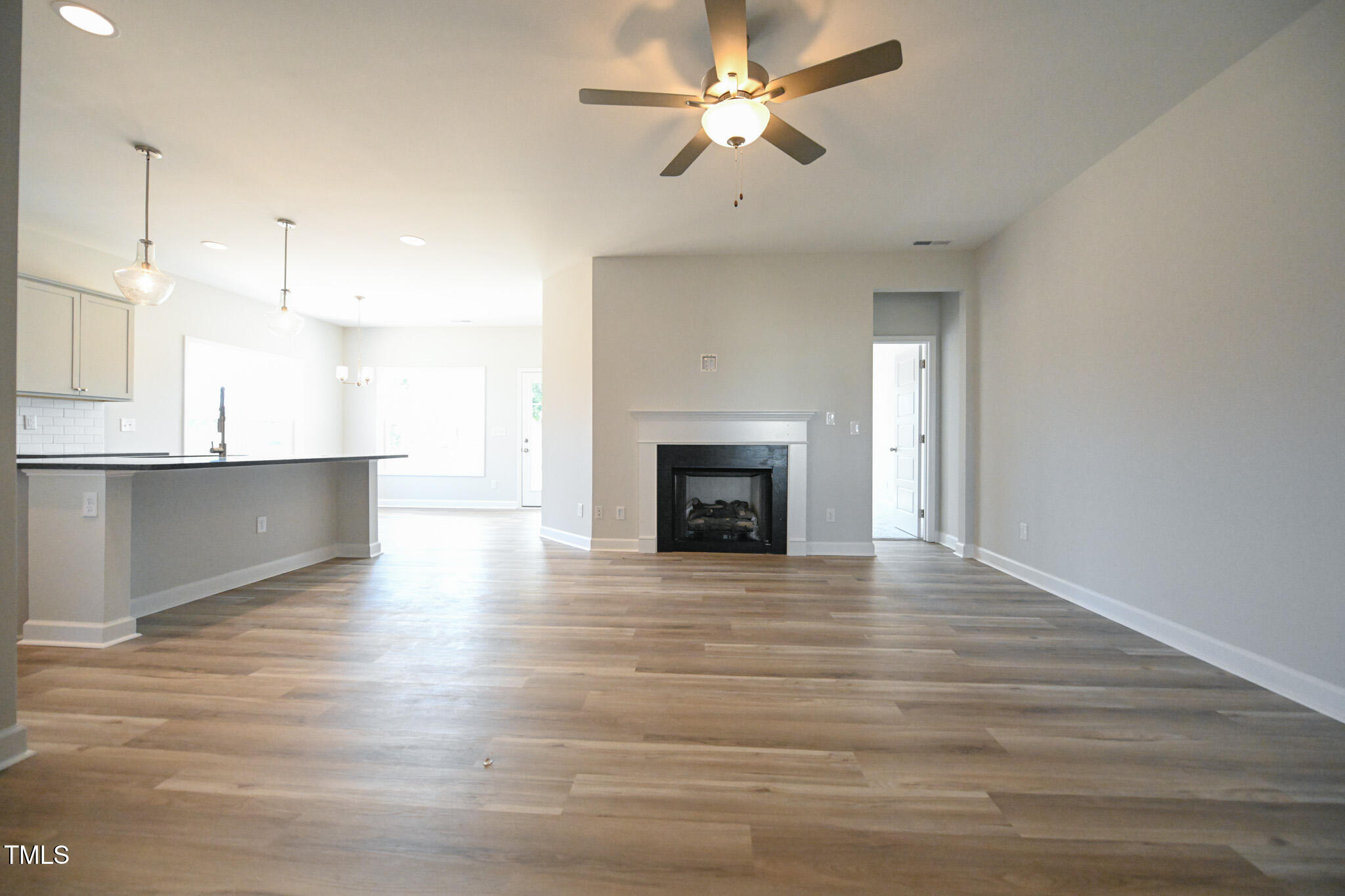 Open-plan living room with a fireplace, wood-look flooring, and kitchen breakfast bar.