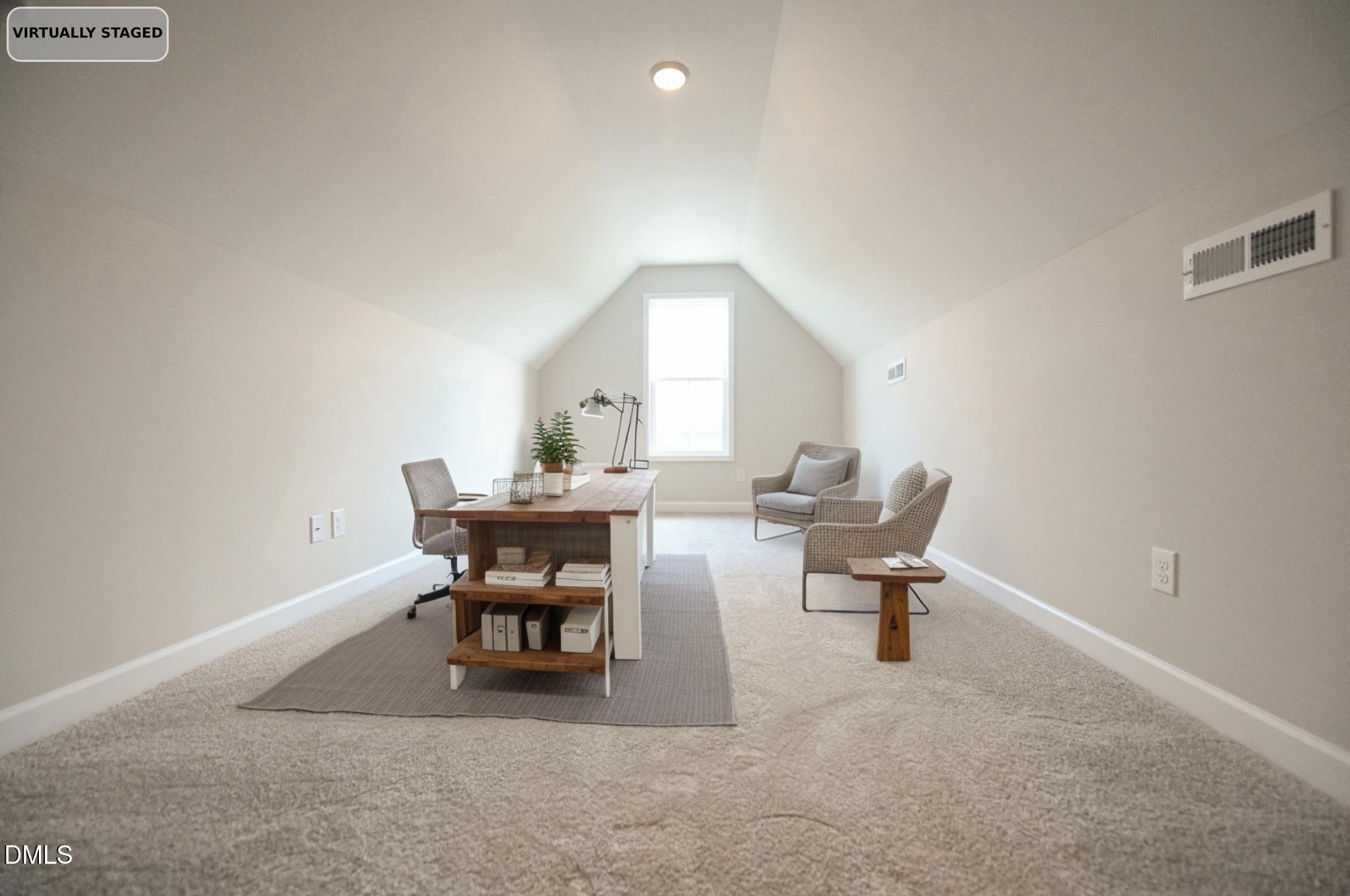 Virtually staged attic office with a vaulted ceiling, desk, two armchairs, and a bright end window.