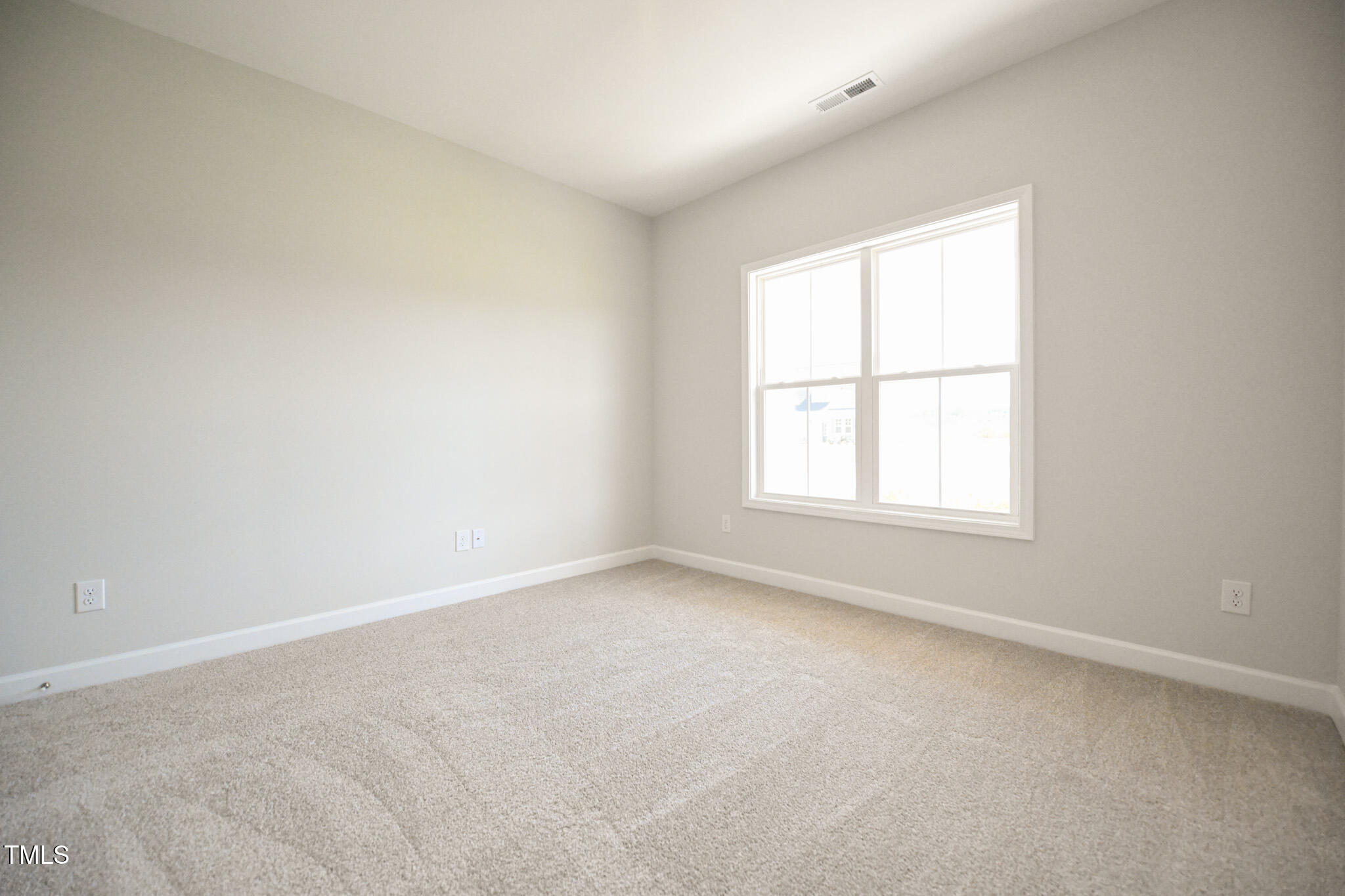 Empty carpeted room with neutral walls and a large multipane window.