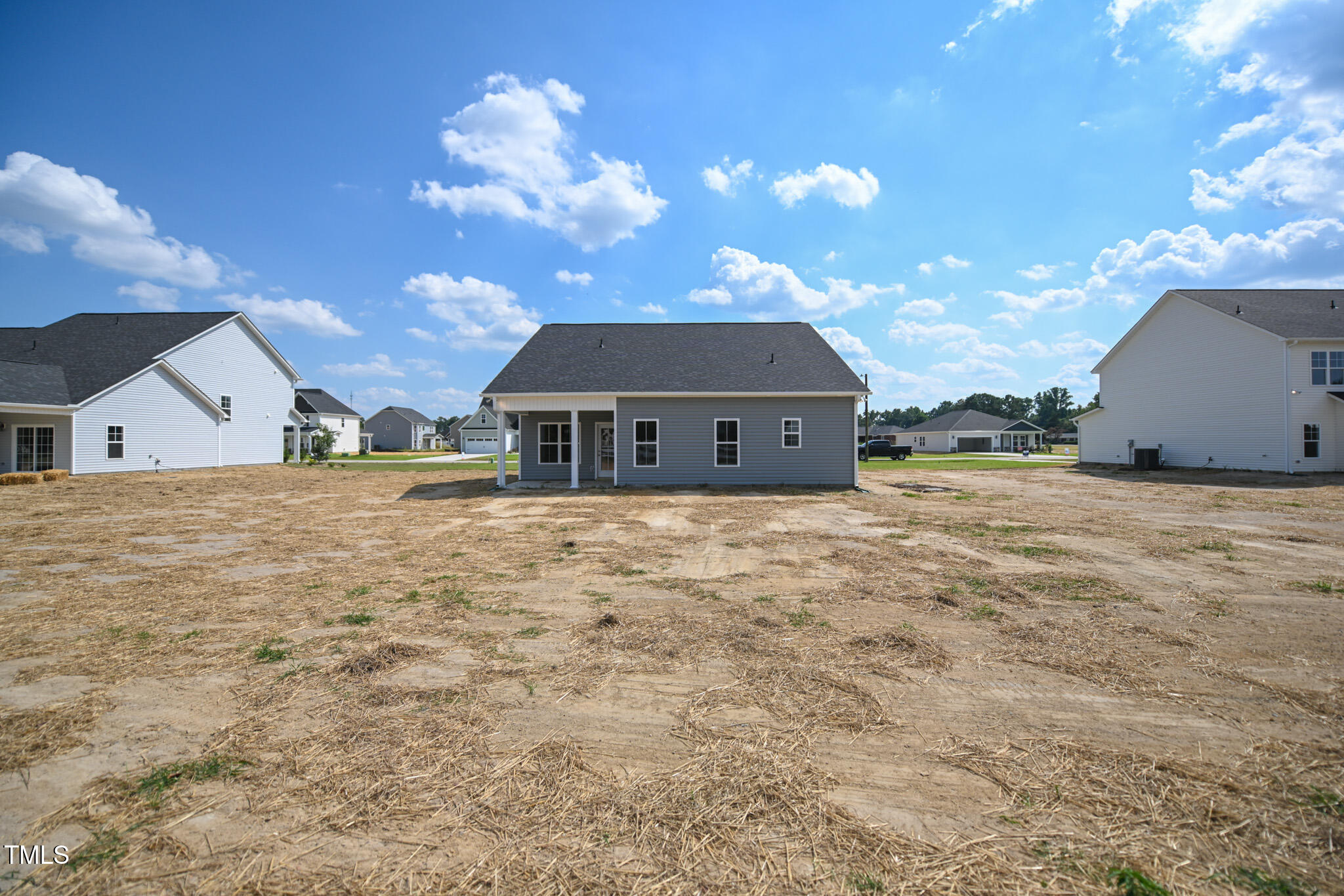 Rear of a gray single-story house with a covered patio and mostly bare yard.