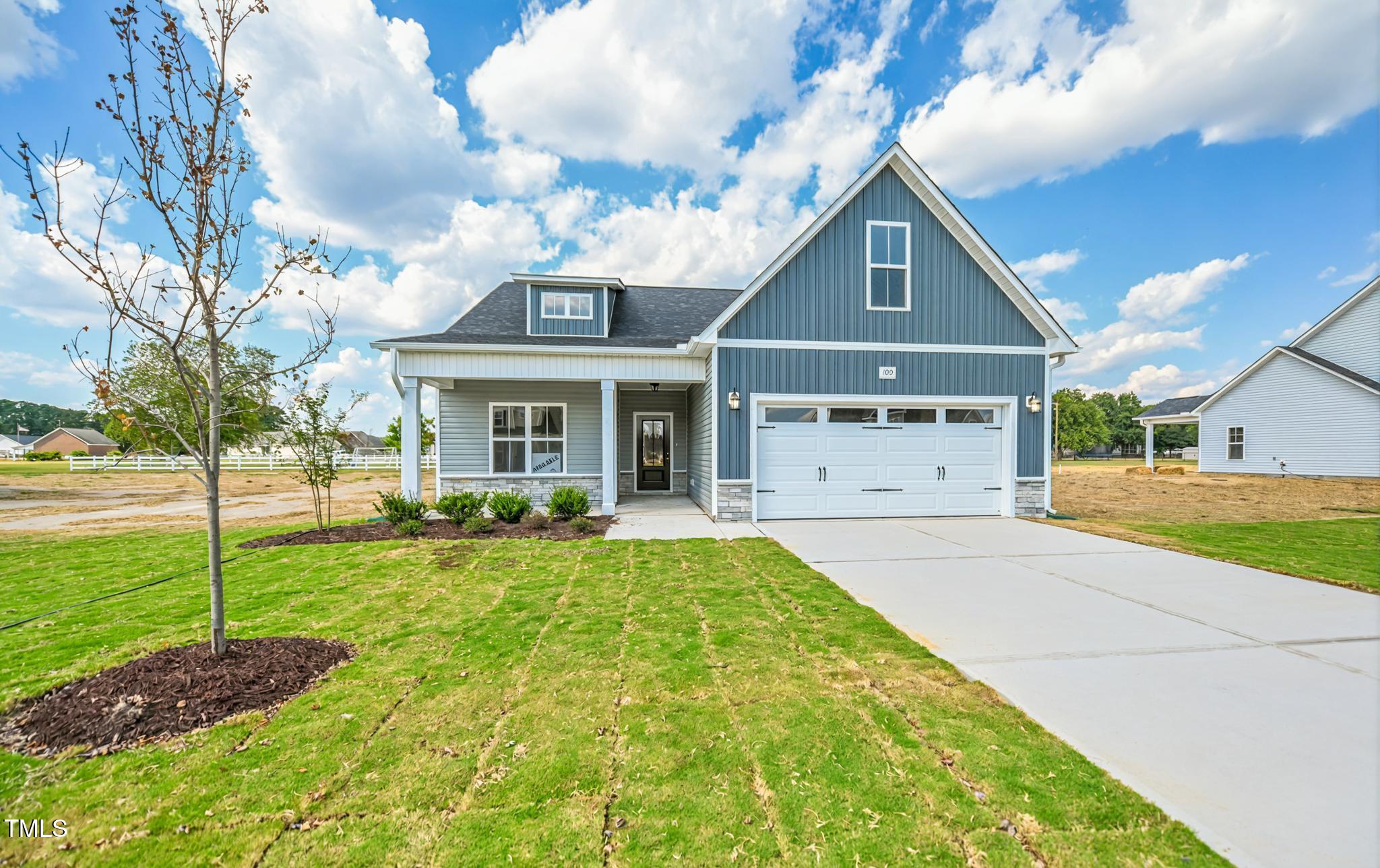 Blue-gray two-story home with white trim, a two-car garage, and a wide concrete driveway.