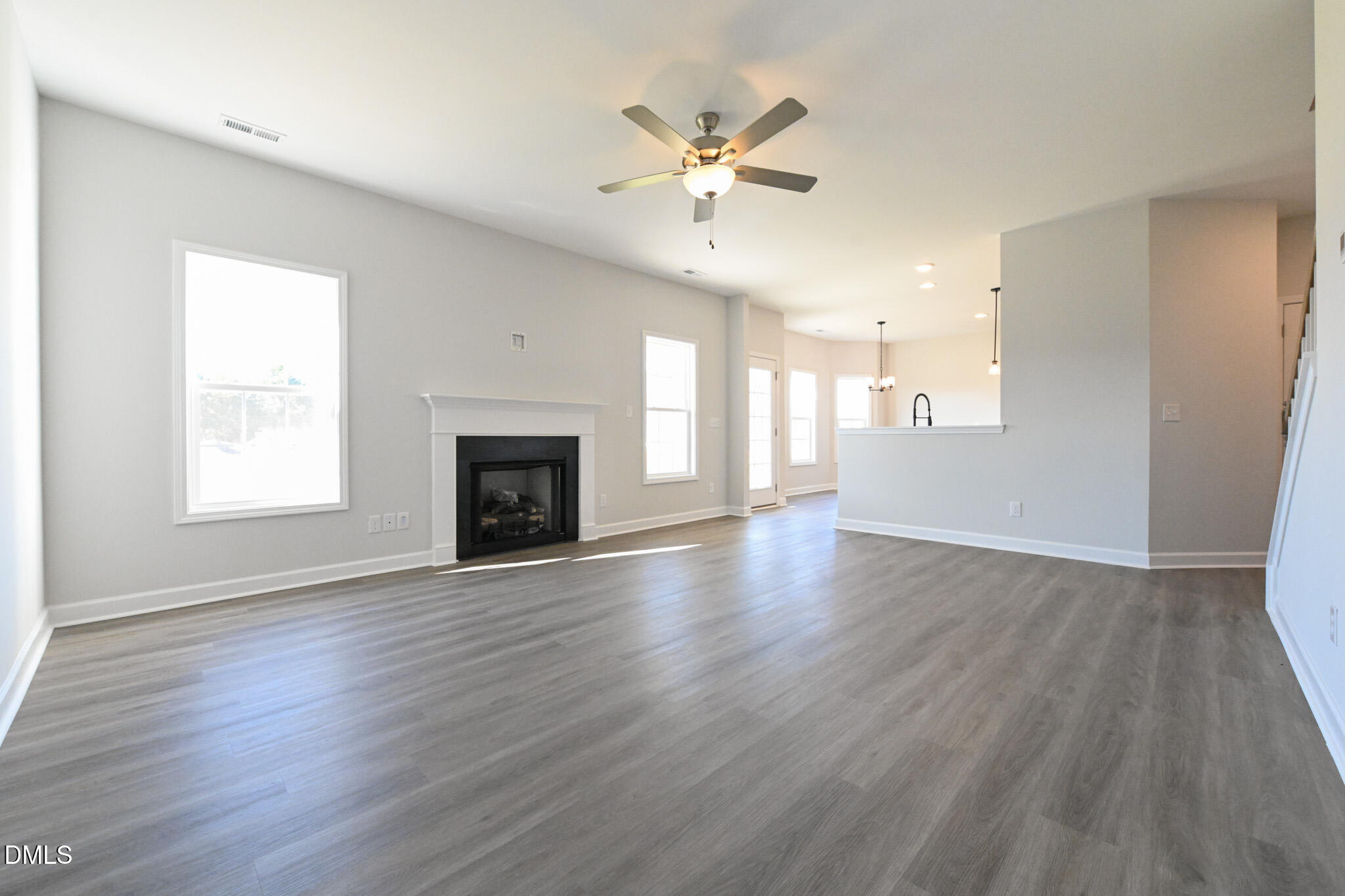 Unfurnished living room with gray plank flooring, a fireplace, and an open kitchen area.