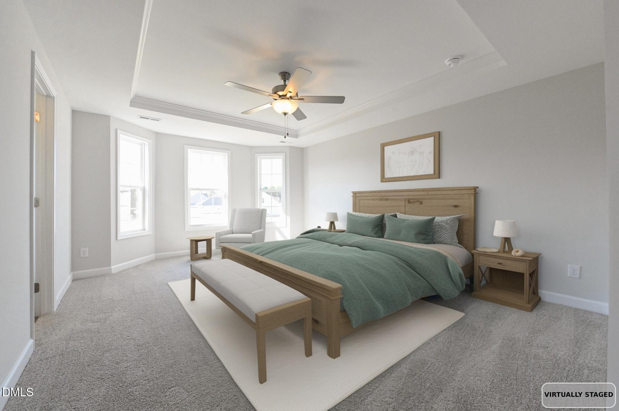 Bedroom with a green-covered bed, wood furnishings, three windows, and a tray ceiling with a fan.