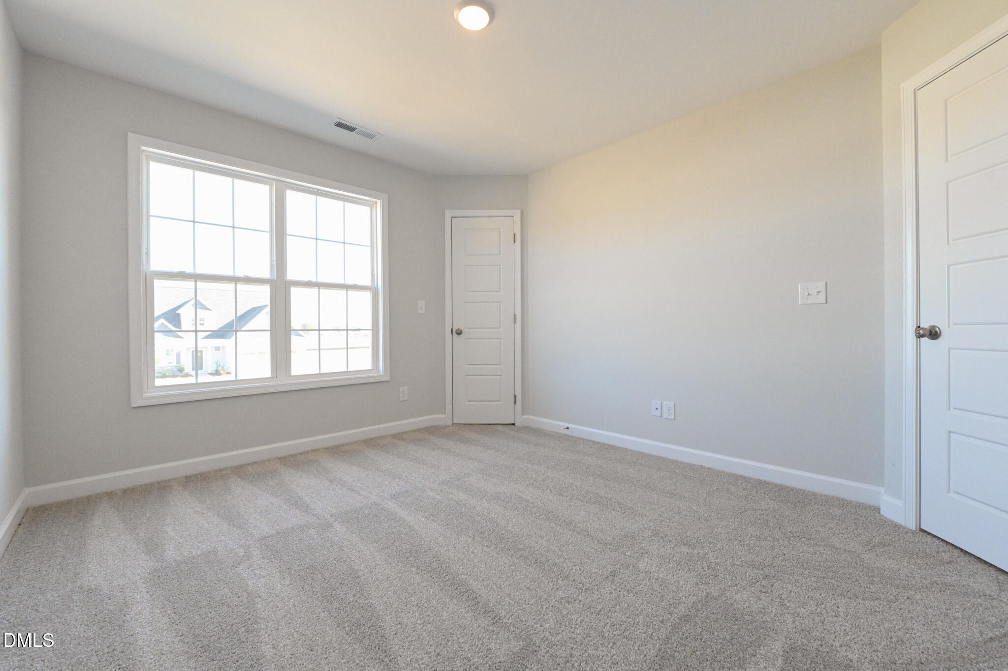 Vacant bedroom with beige carpet, gray walls, and a large window.