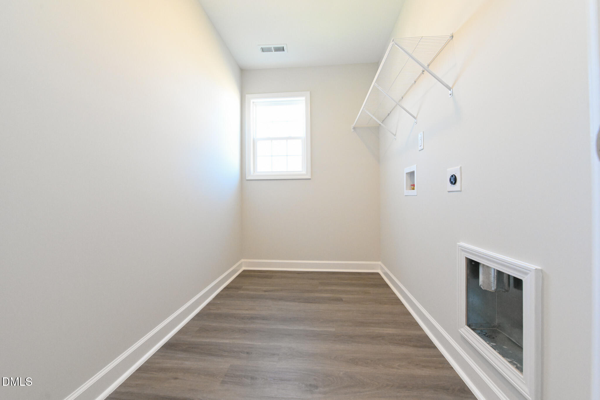 Empty laundry room with wire shelf, washer and dryer hookups, and a small window.