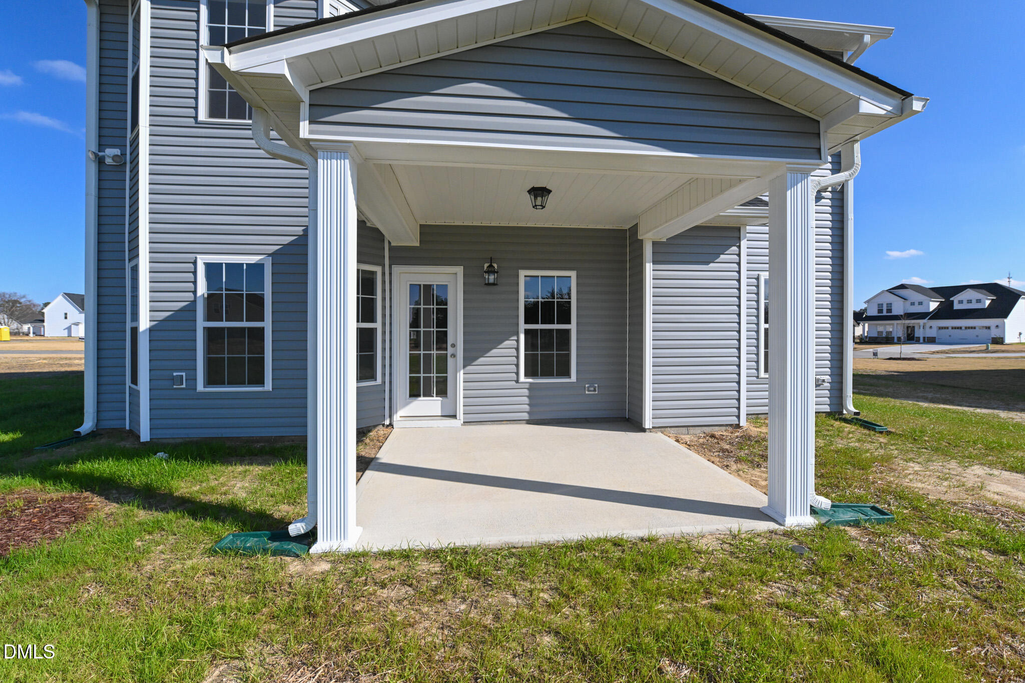 Gray house with a covered concrete patio, white columns, and glass-paneled door.