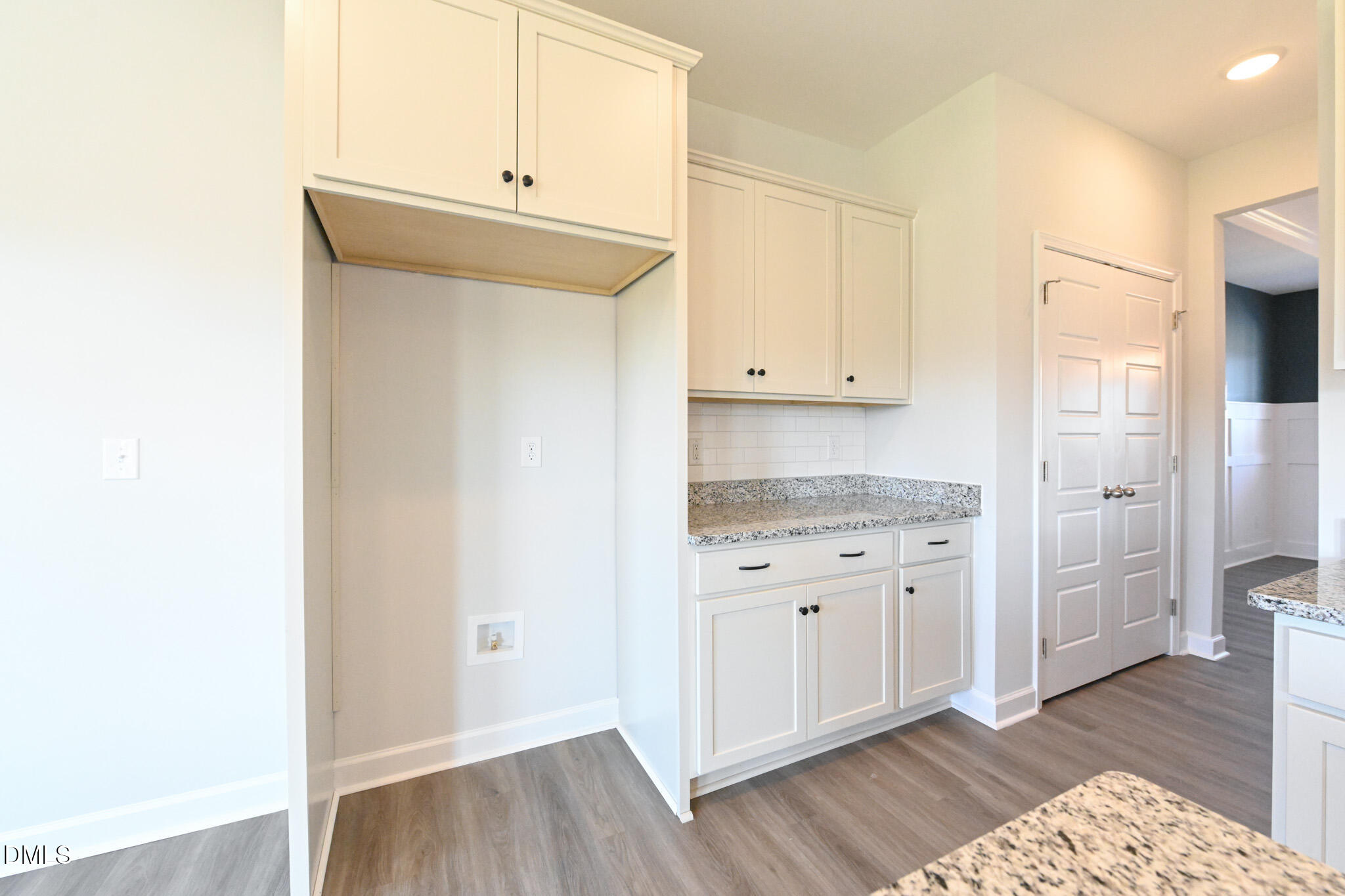 Kitchen with white shaker cabinets, granite countertops, and a recessed laundry nook.