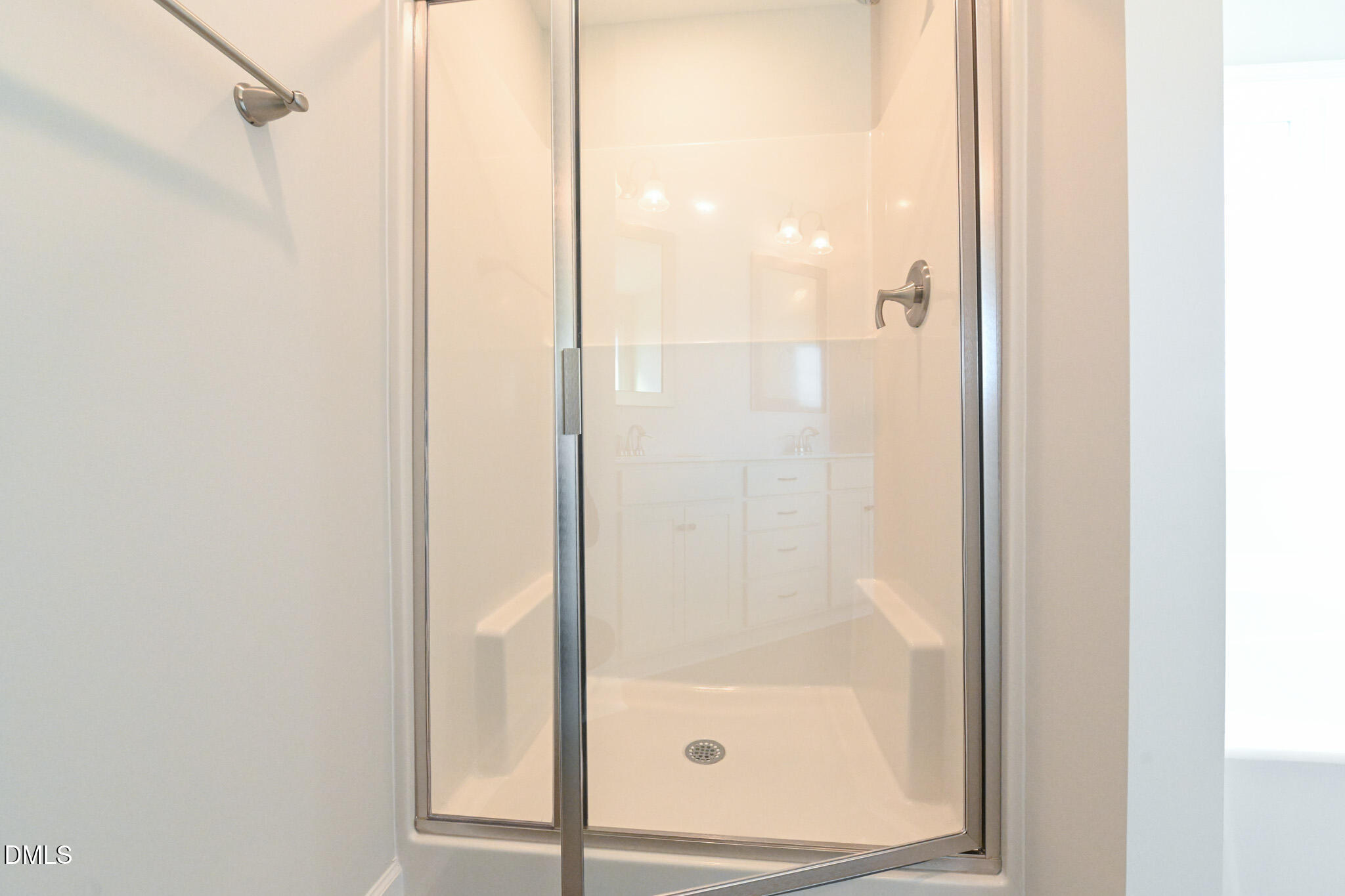 Glass-enclosed shower with chrome fixtures and a light-colored shower base.