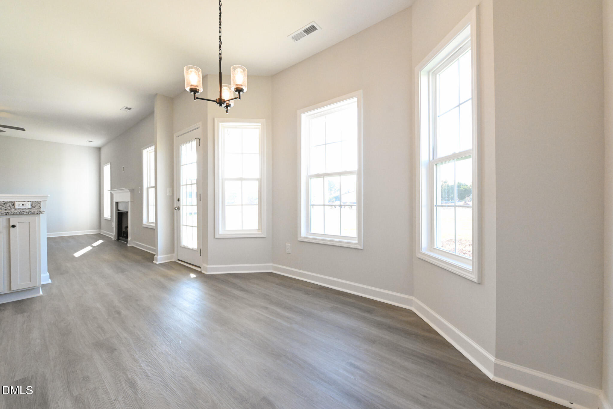 Vacant living room with gray flooring, a fireplace, and large windows.