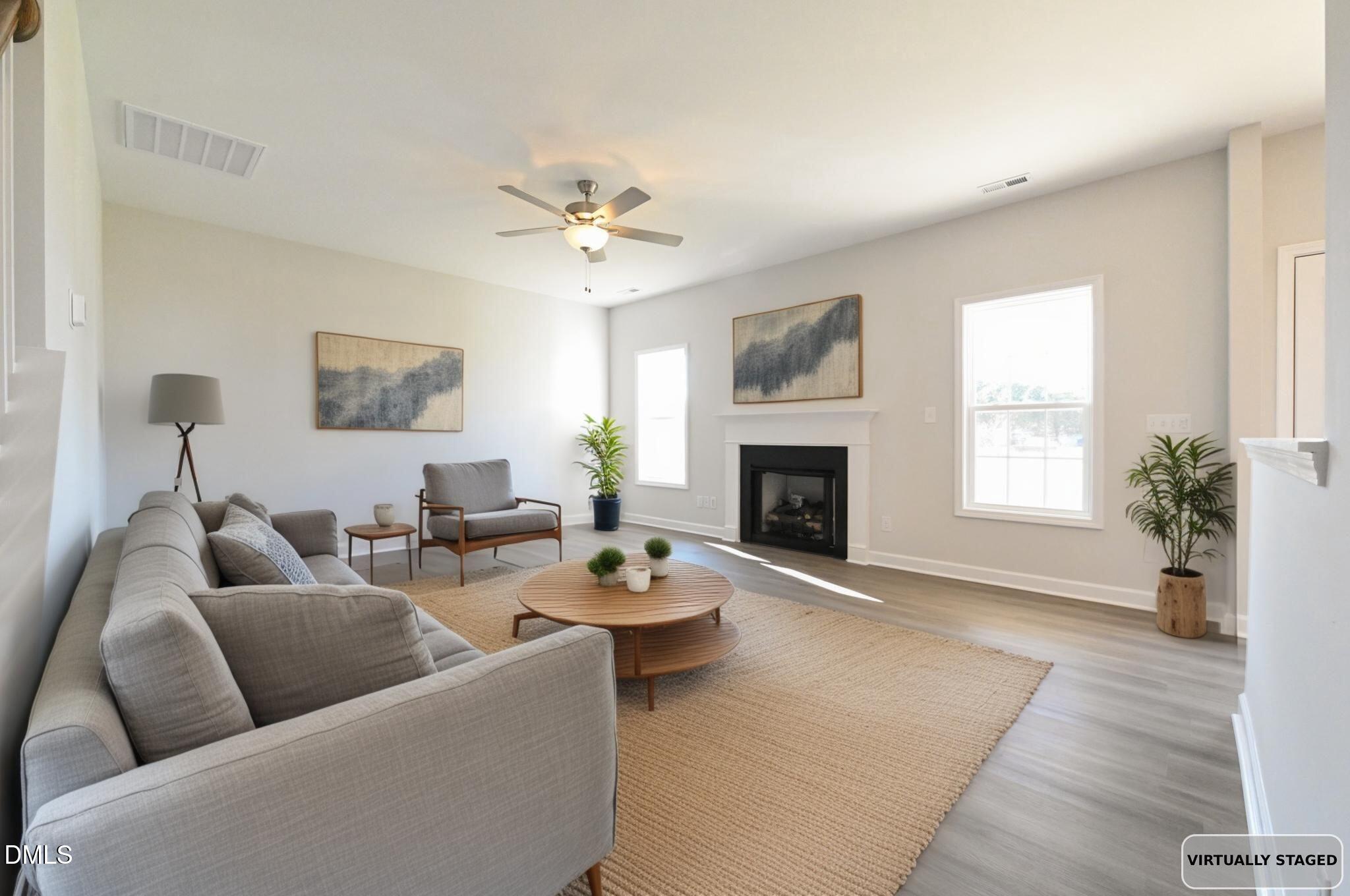 Virtually staged living room with gray seating, a fireplace, and large windows.