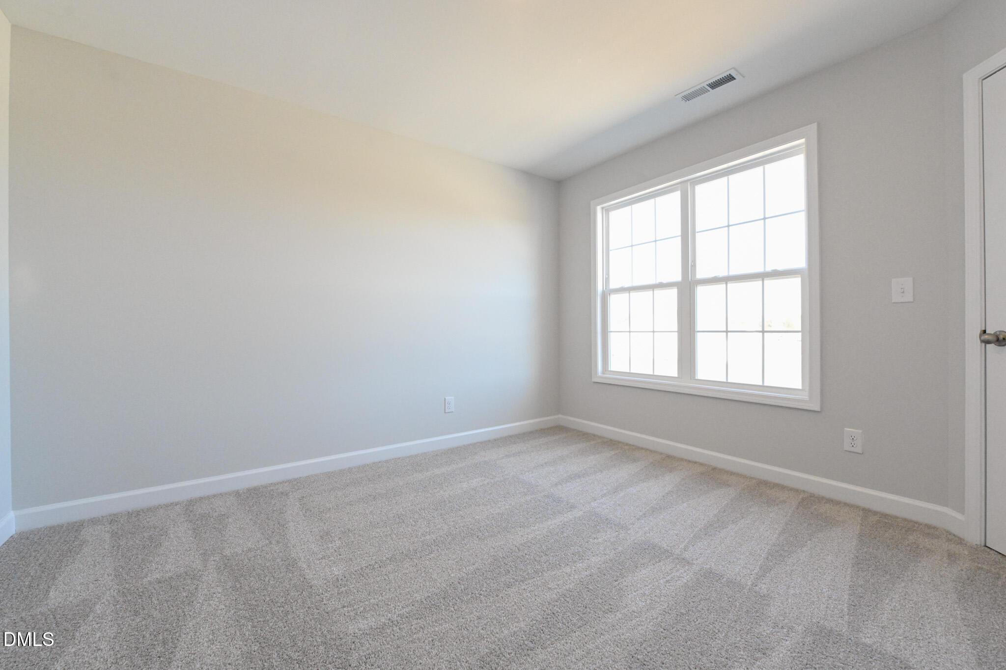 Empty carpeted bedroom with gray walls and a large divided-pane window.