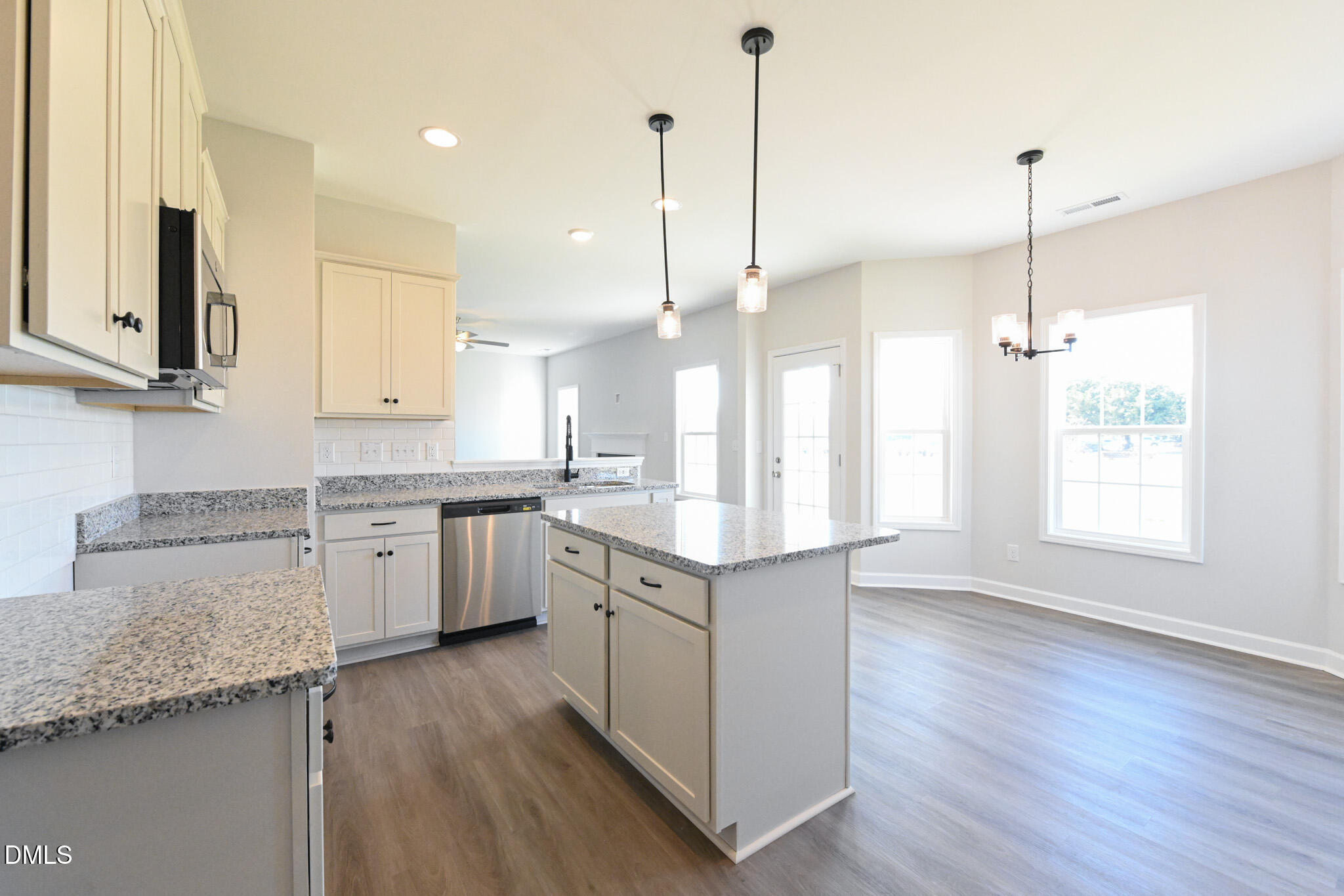 Open-plan kitchen with granite counters, a central island, and bright dining area with large windows.