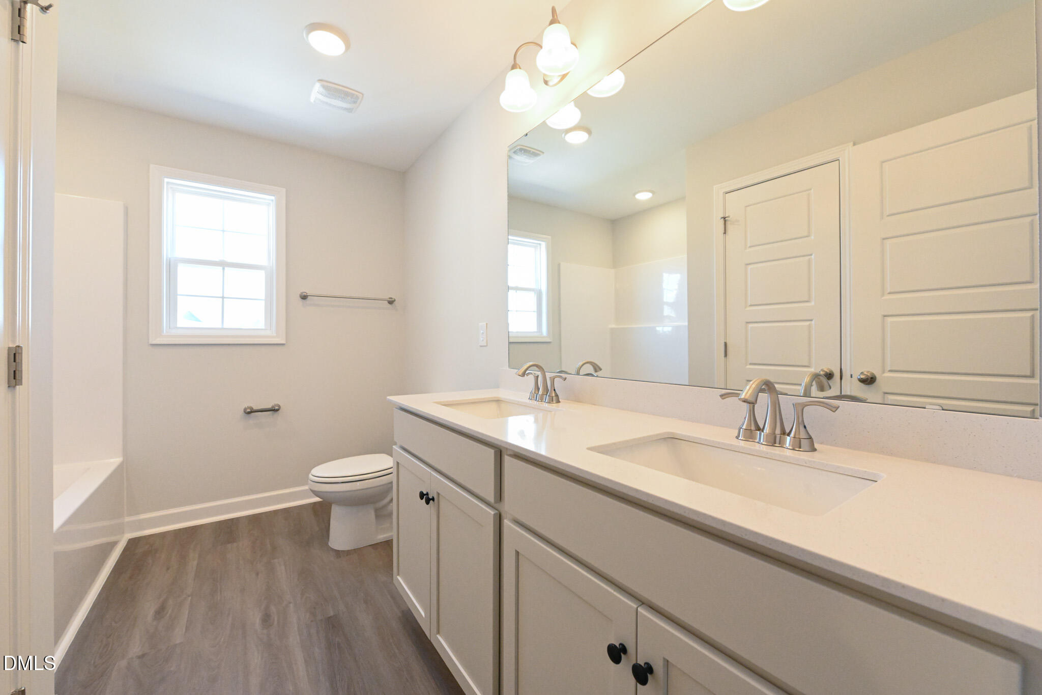 Bathroom with a double-sink vanity, large mirror, and tub-shower alcove.