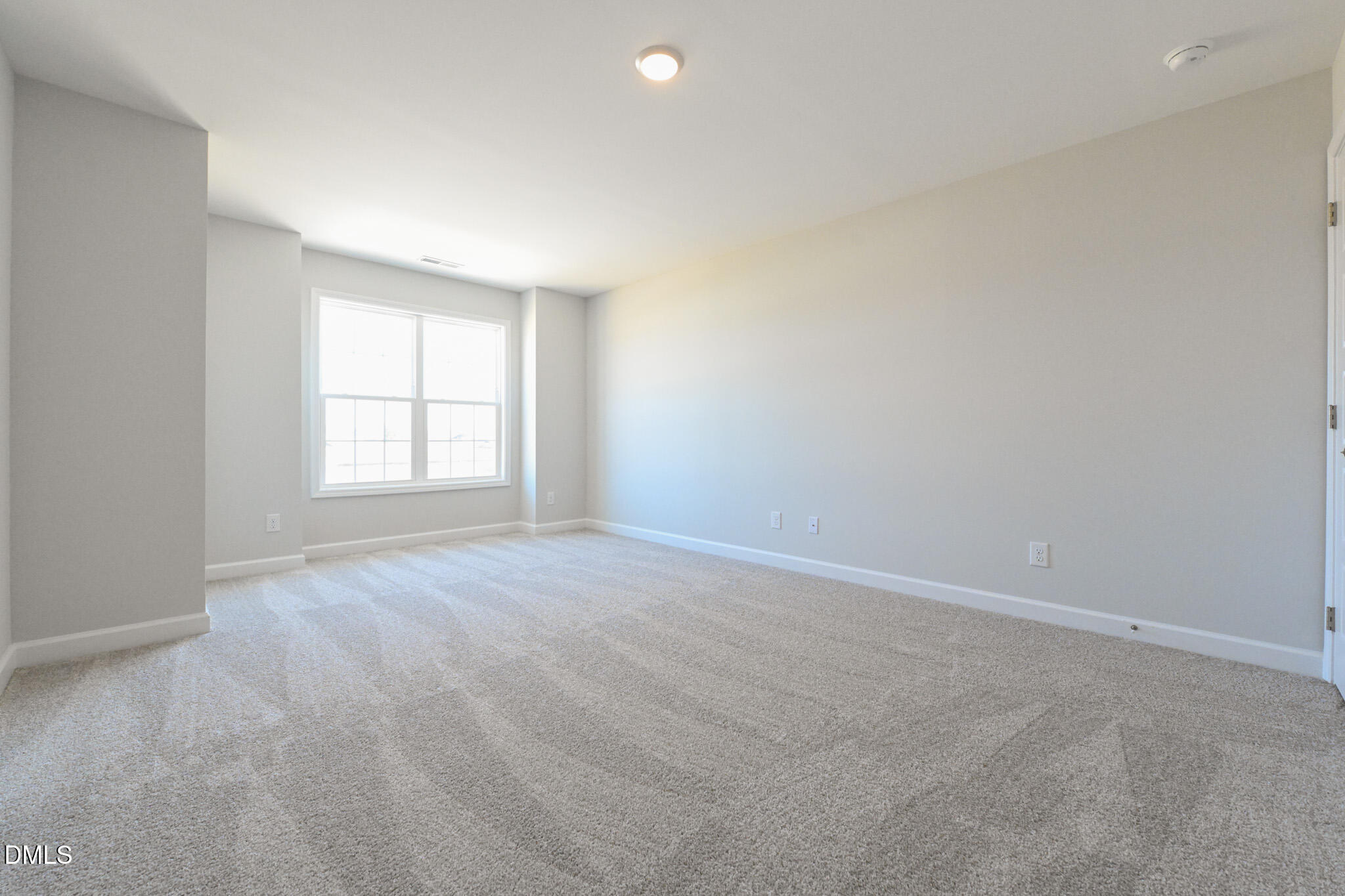 Empty carpeted room with gray walls, a large window, and a ceiling light.