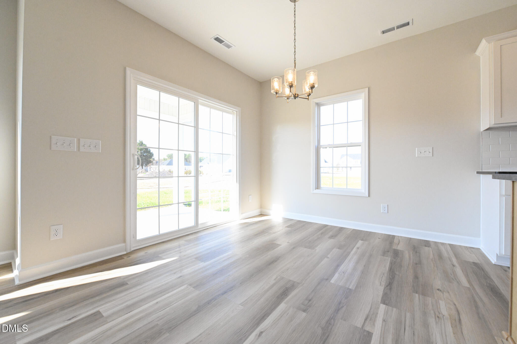Vacant dining area with gray flooring, a chandelier, and sliding glass doors.