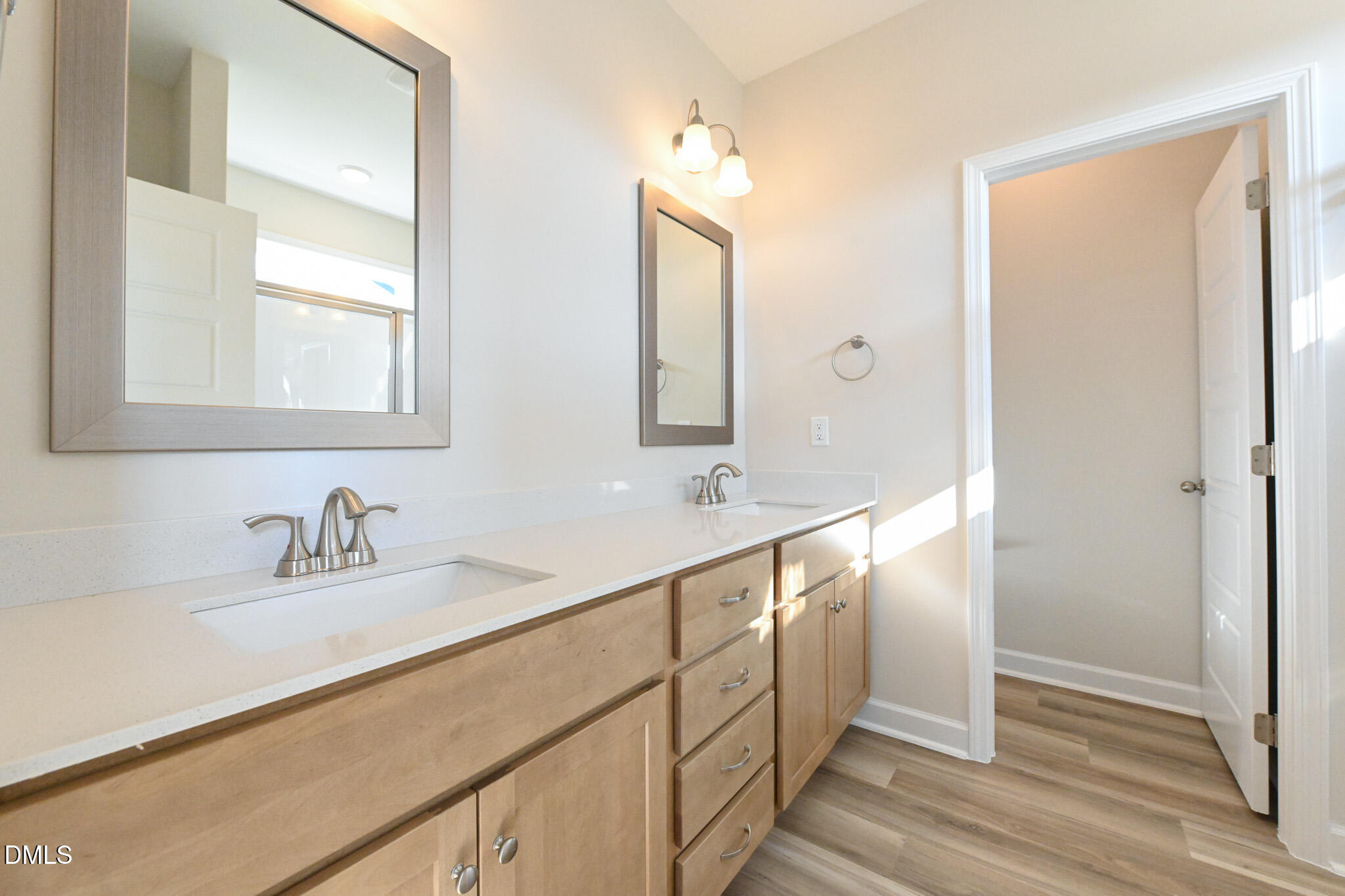 Bathroom with a long double-sink vanity, wood-tone cabinets, and framed mirrors.
