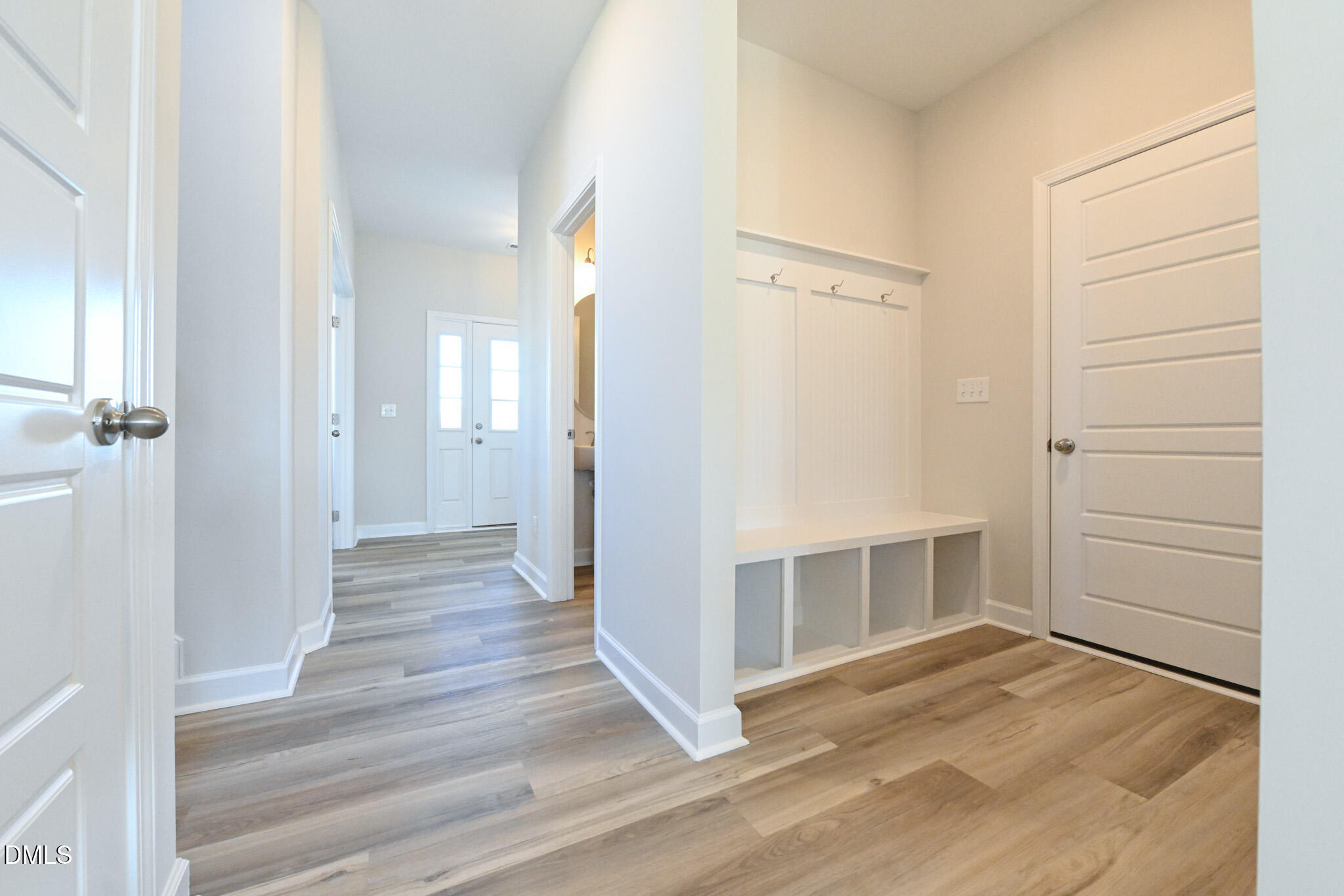Entryway with a built-in bench, open cubbies, wall hooks, and wood-look flooring.