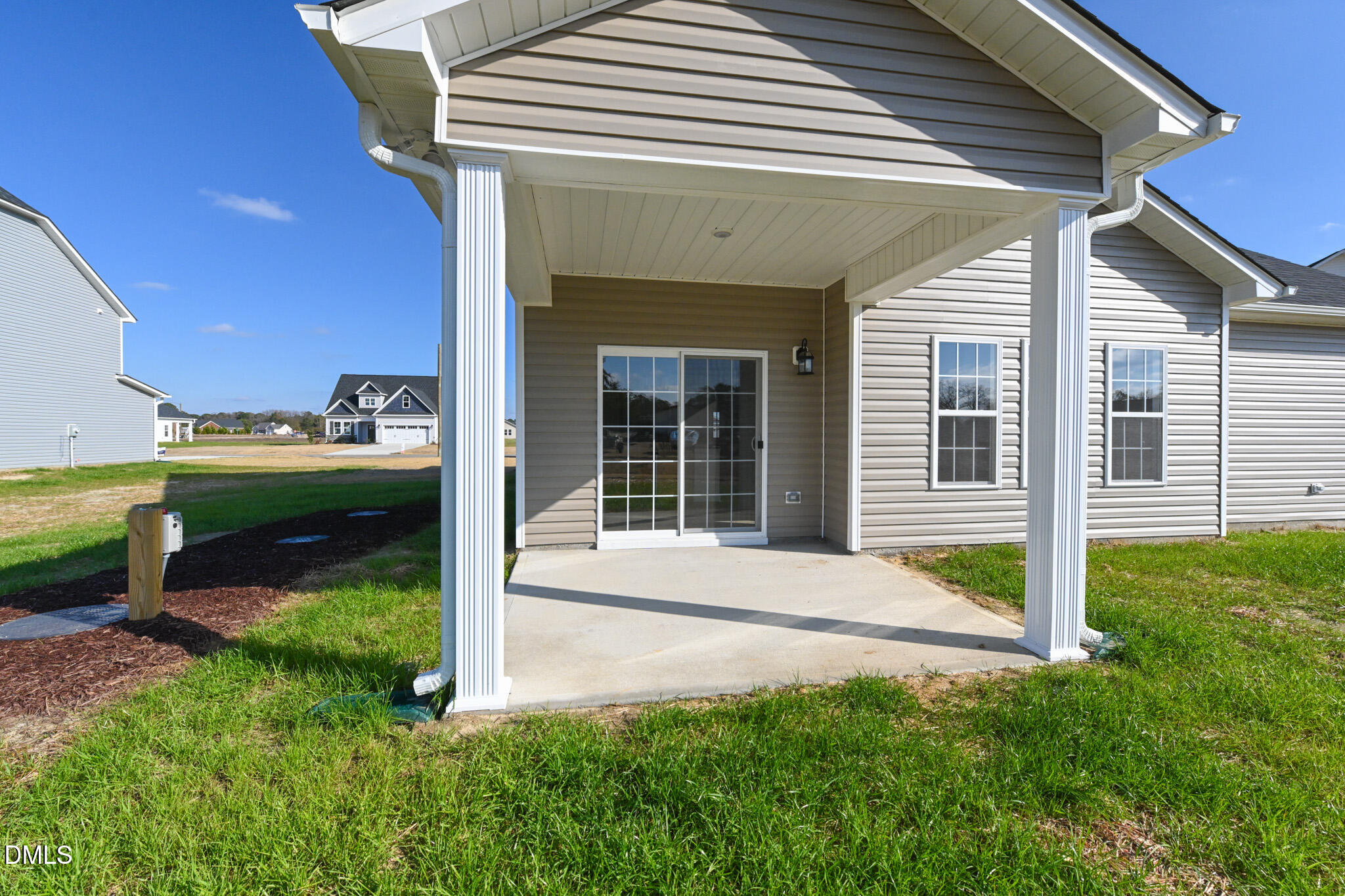 Rear exterior of a home with a covered concrete patio and sliding glass door.