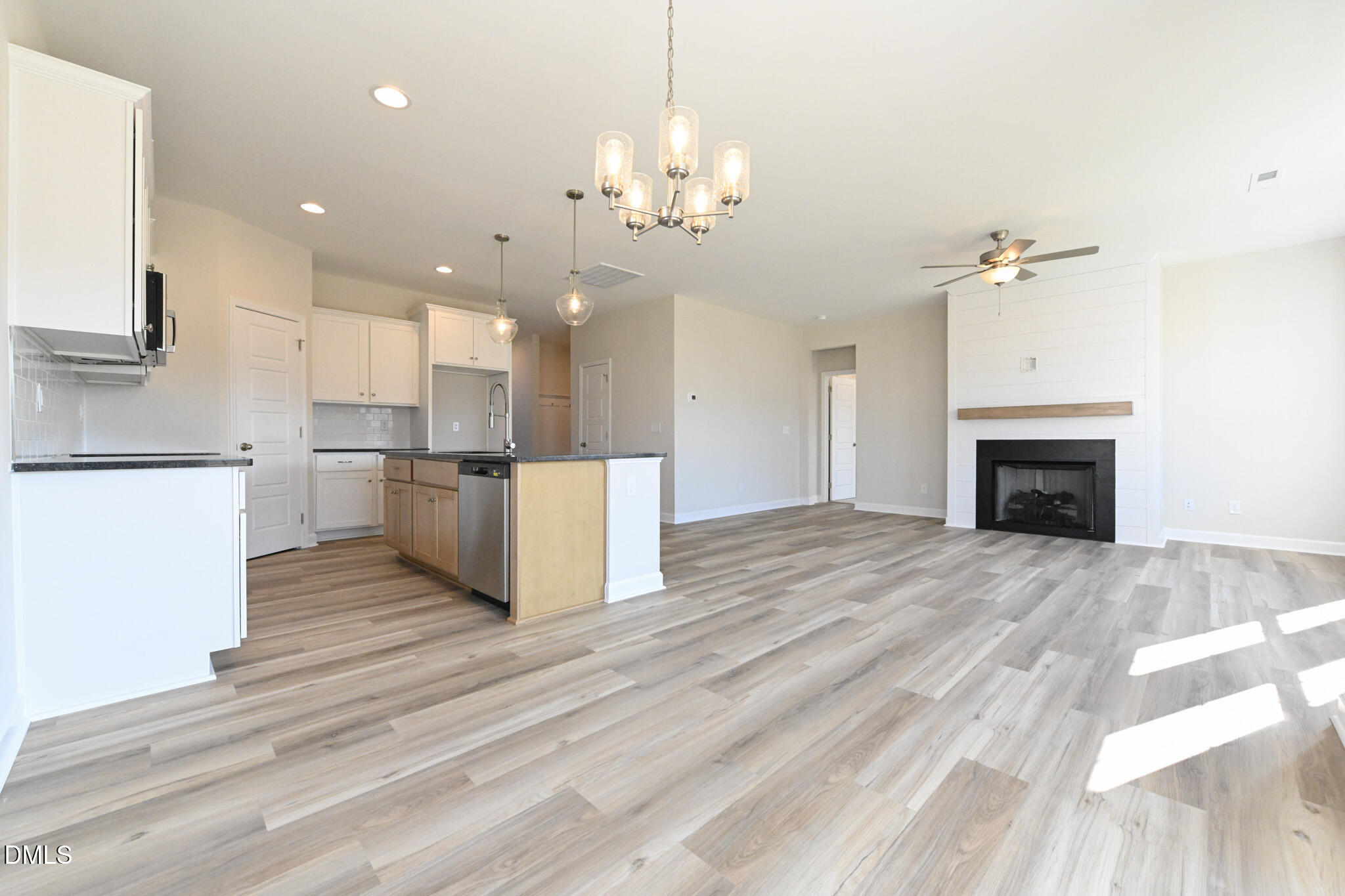 Open kitchen and living area with an island, gray plank flooring, and a fireplace.