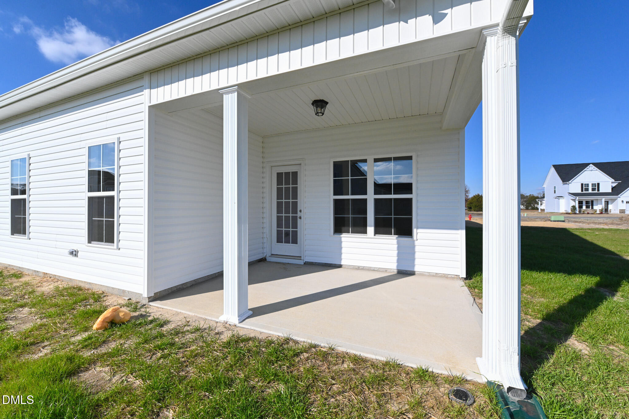 White home with a spacious covered concrete patio and large windows.