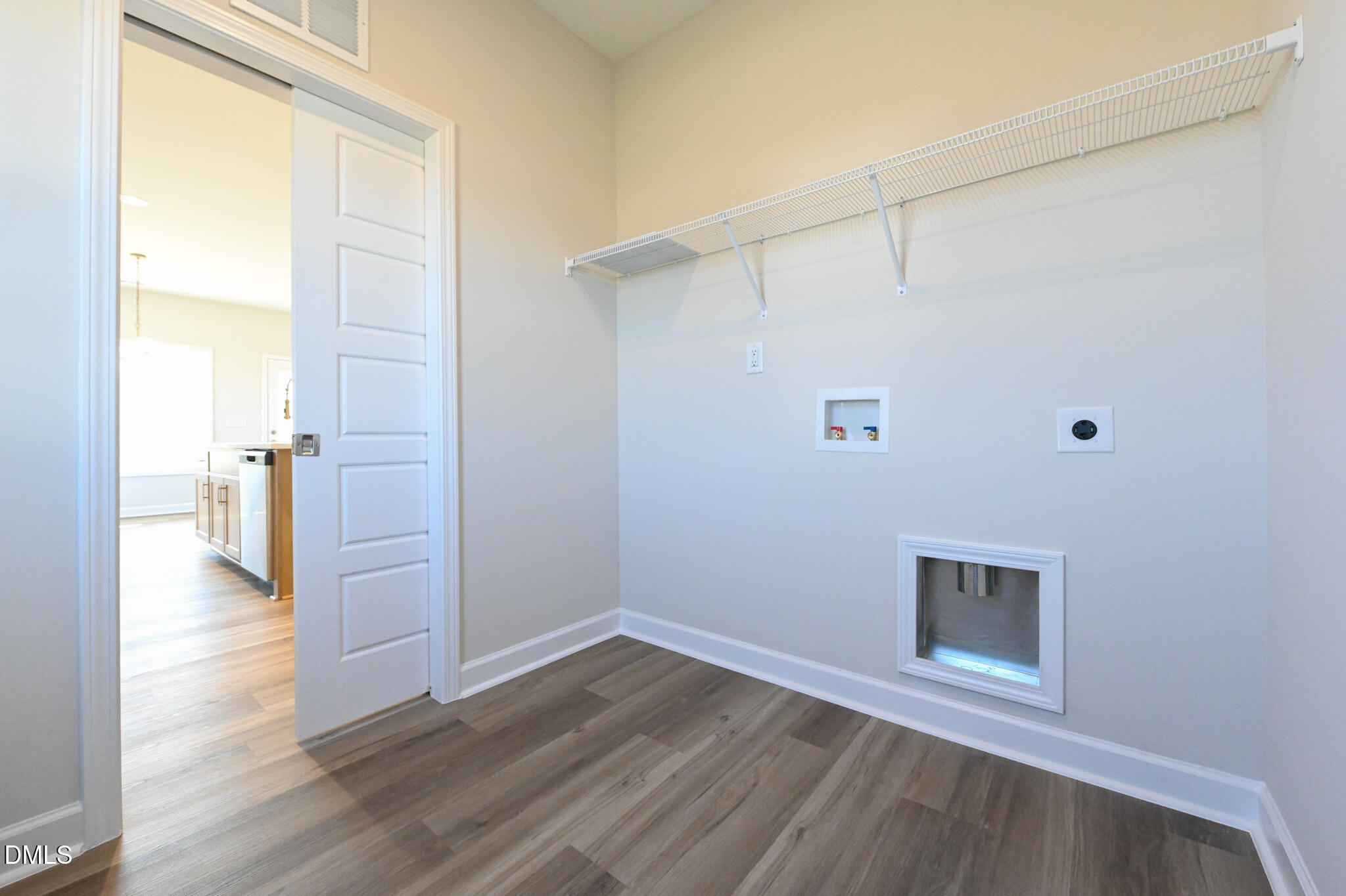 Laundry room with wire shelving, washer and dryer hookups, and wood-look flooring.