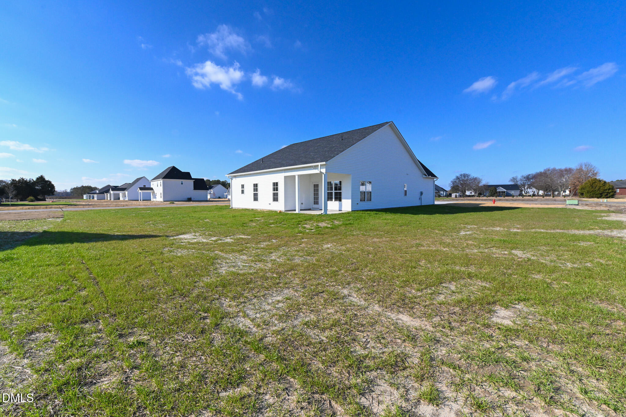 White single-story home with a covered rear porch on a broad, newly seeded lot.