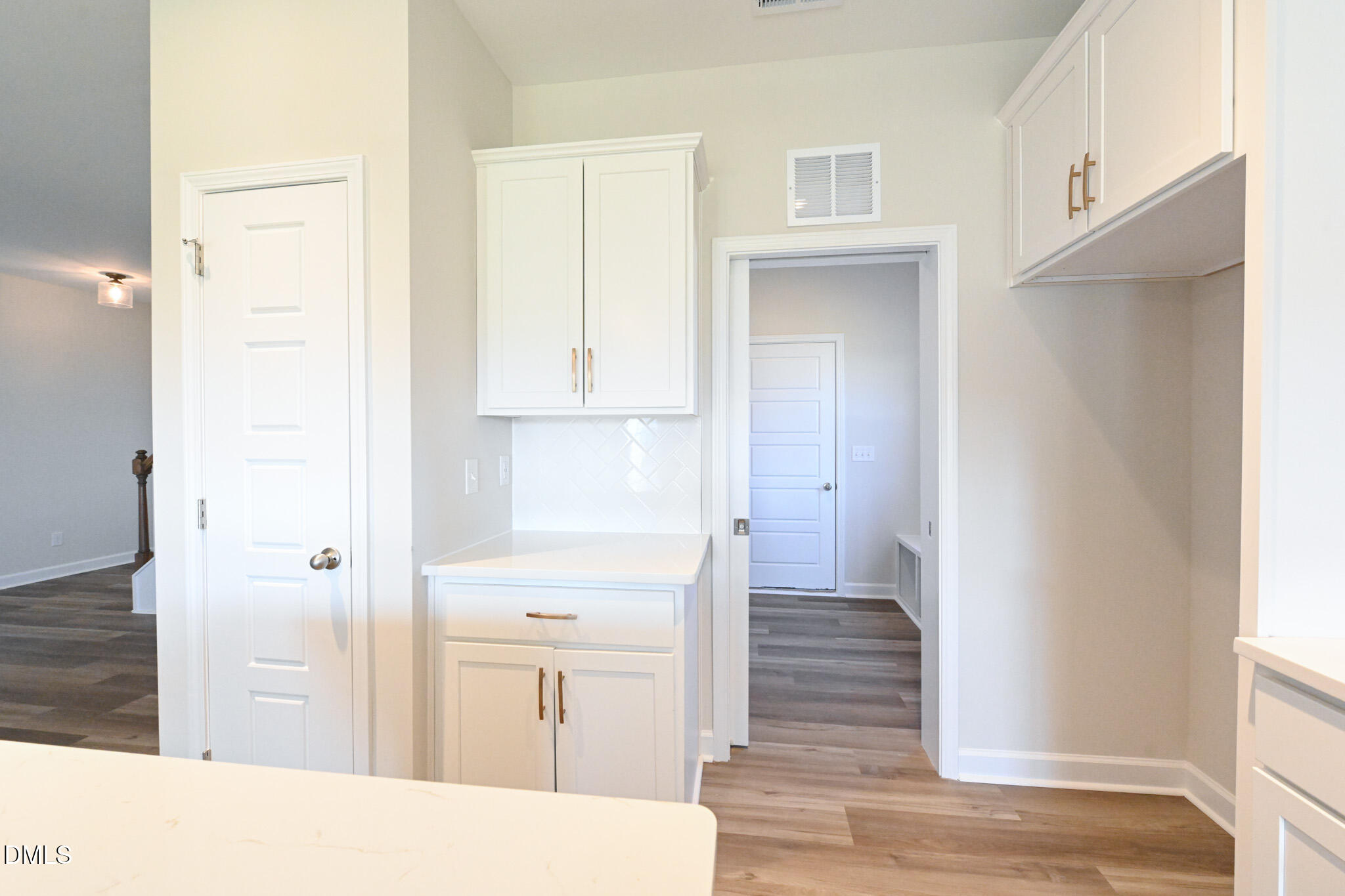 Kitchen with white shaker cabinets, brass-colored handles, and a tile backsplash.