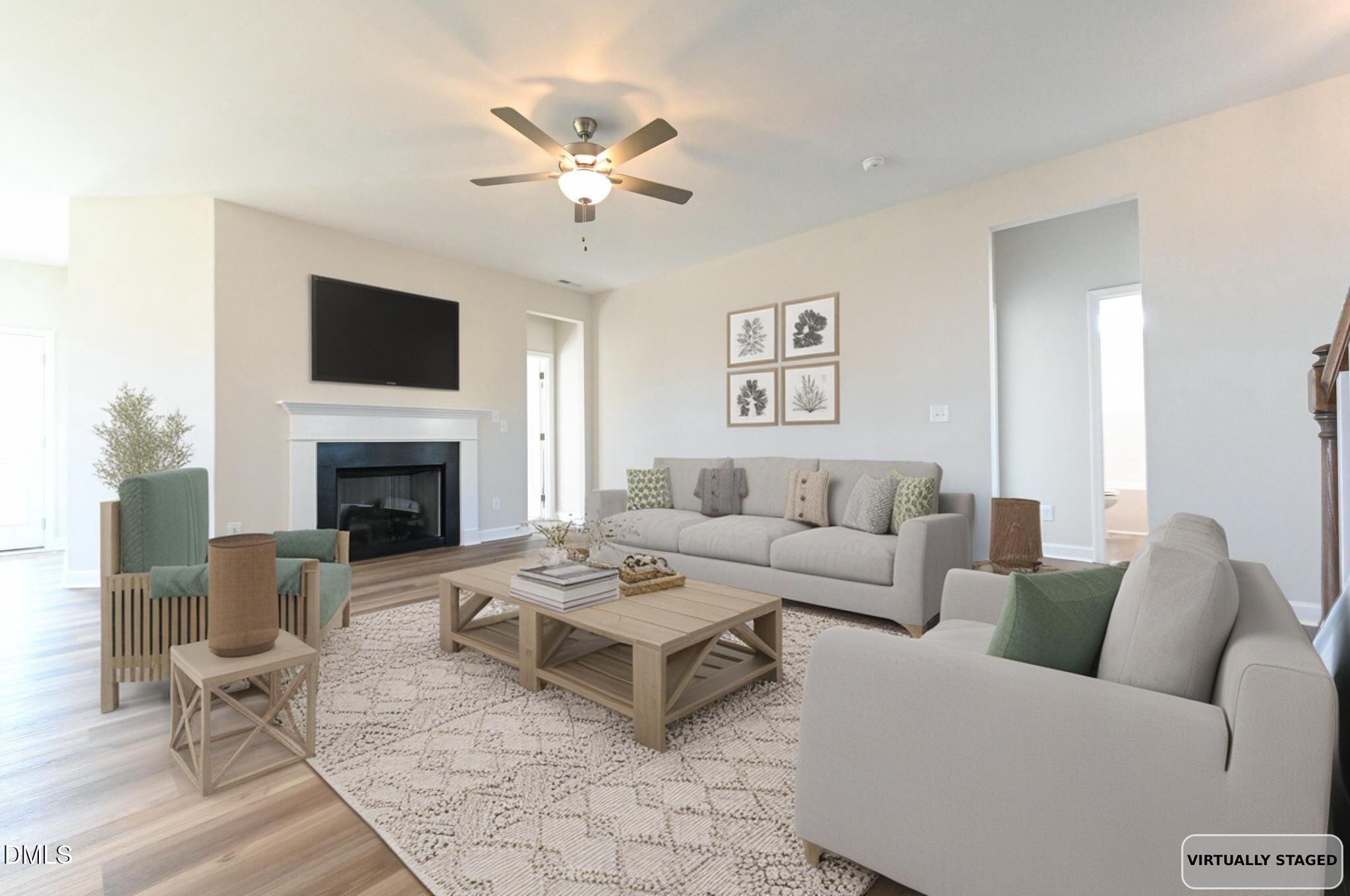 Living room with a white fireplace, wall-mounted TV, neutral sofas, and green accent chairs.