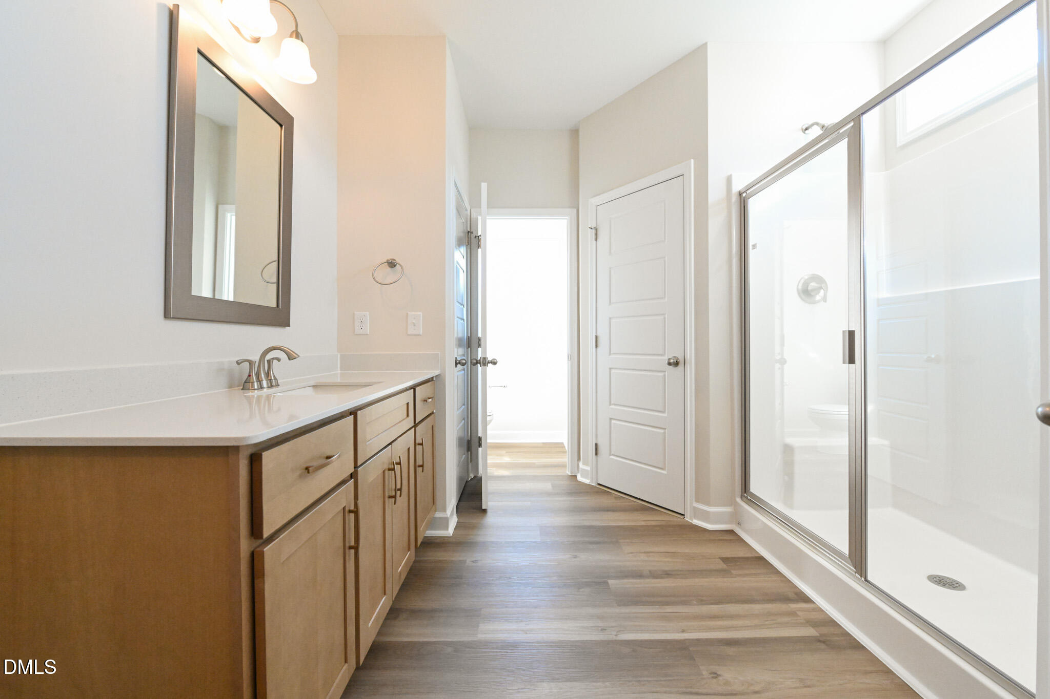 Bathroom with a long wood vanity and glass-enclosed walk-in shower.
