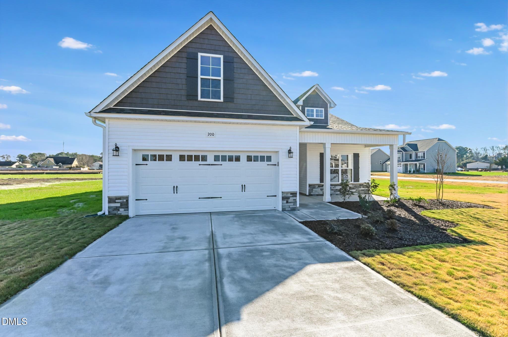 House exterior with a broad concrete driveway, two-car garage, and covered front porch.