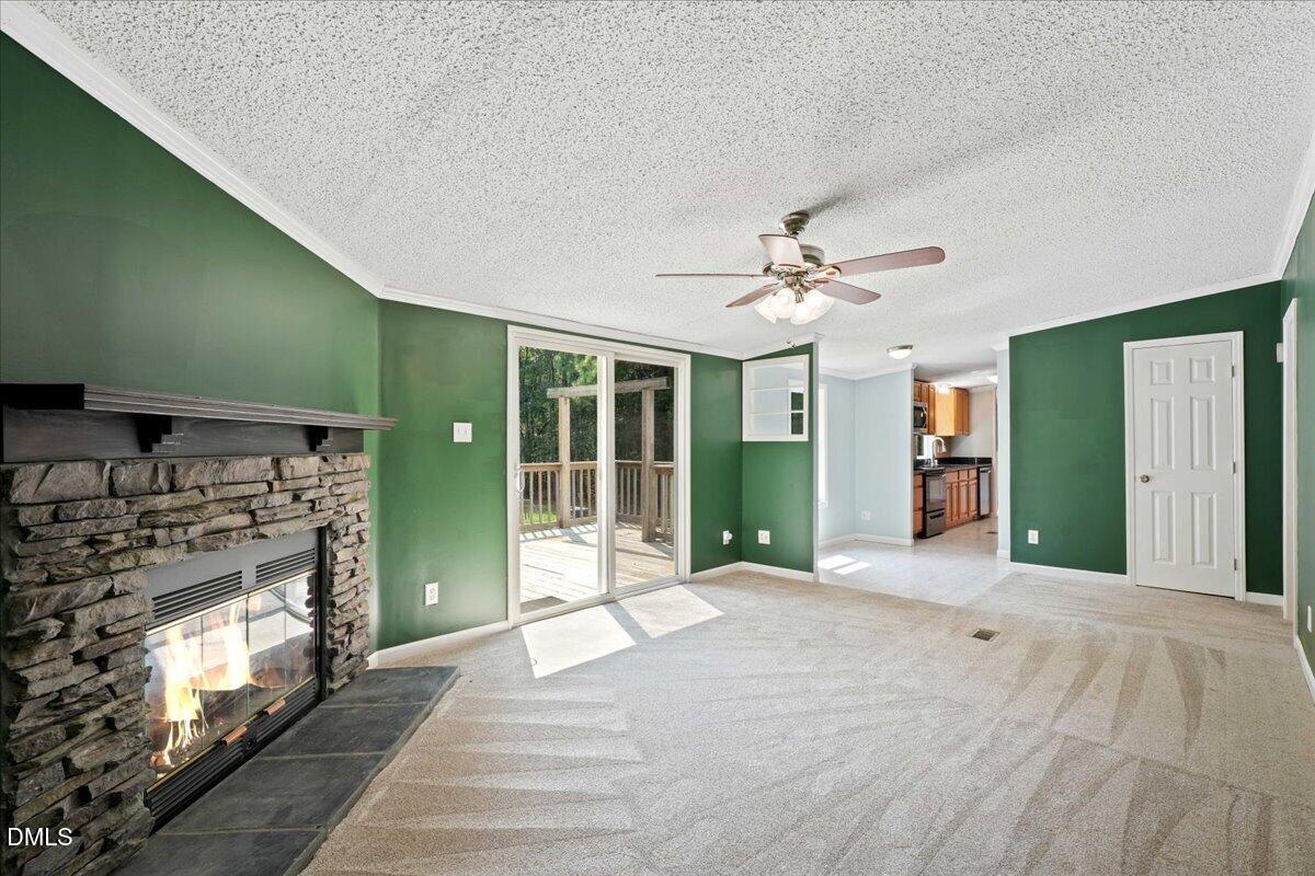 Unfurnished living room with a stone fireplace, green walls, and sliding doors to a deck.