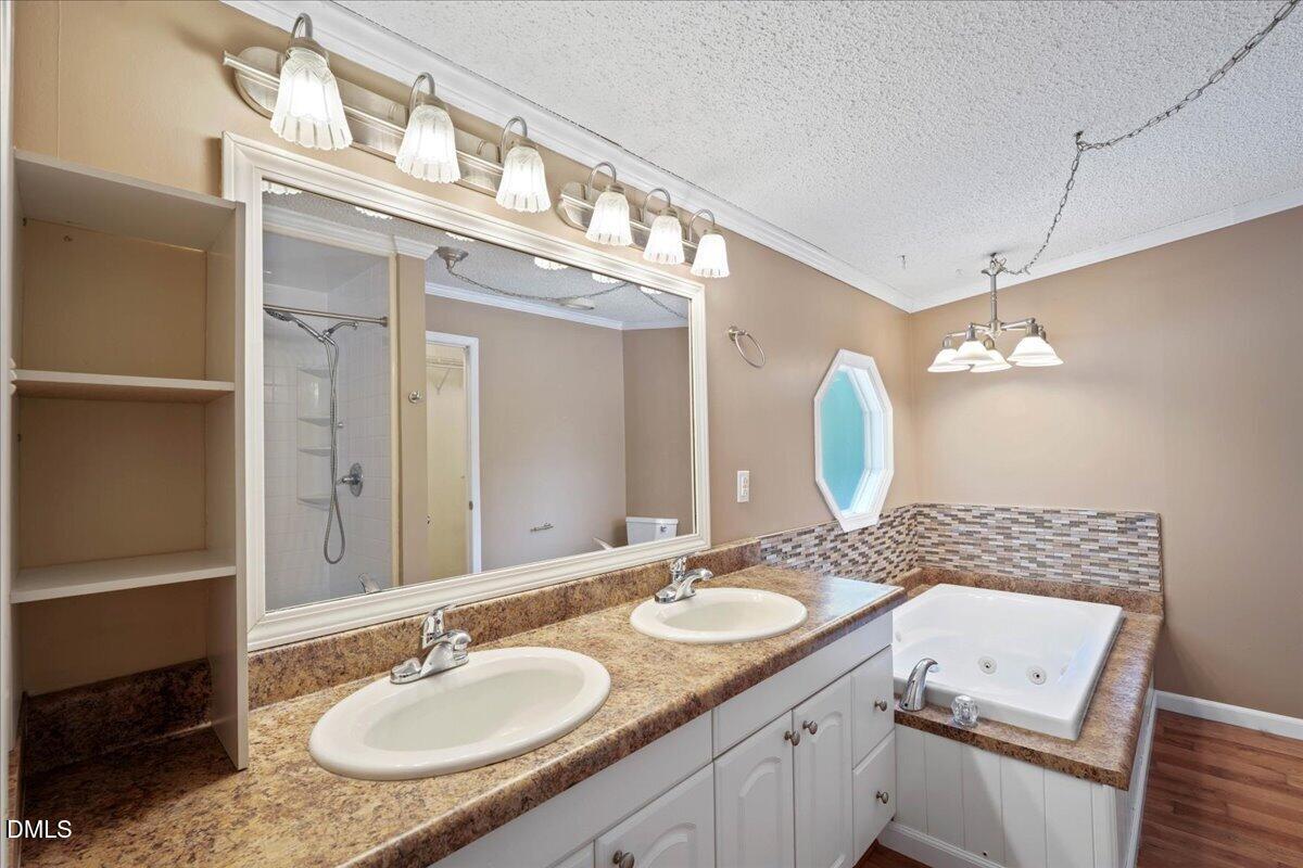 Bathroom with a double-sink vanity, large mirror, and jetted tub.