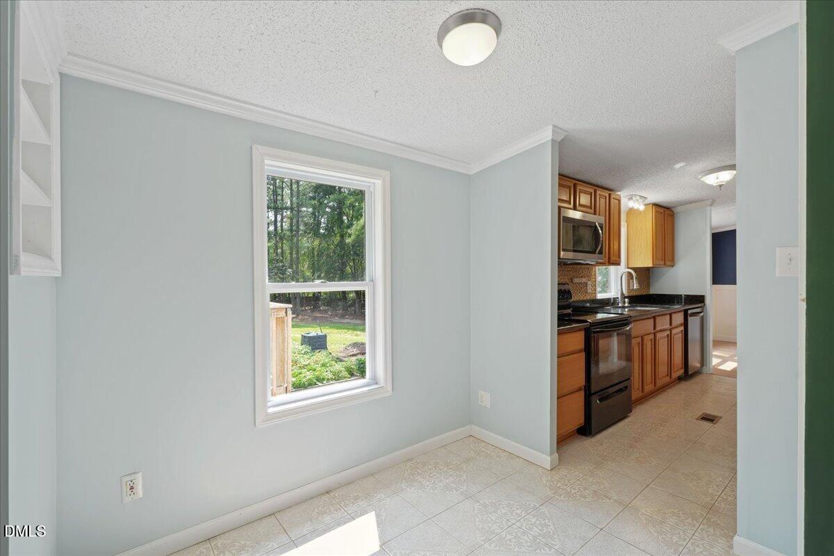 Empty dining area opening into a wood-cabinet kitchen, with a window overlooking the yard.